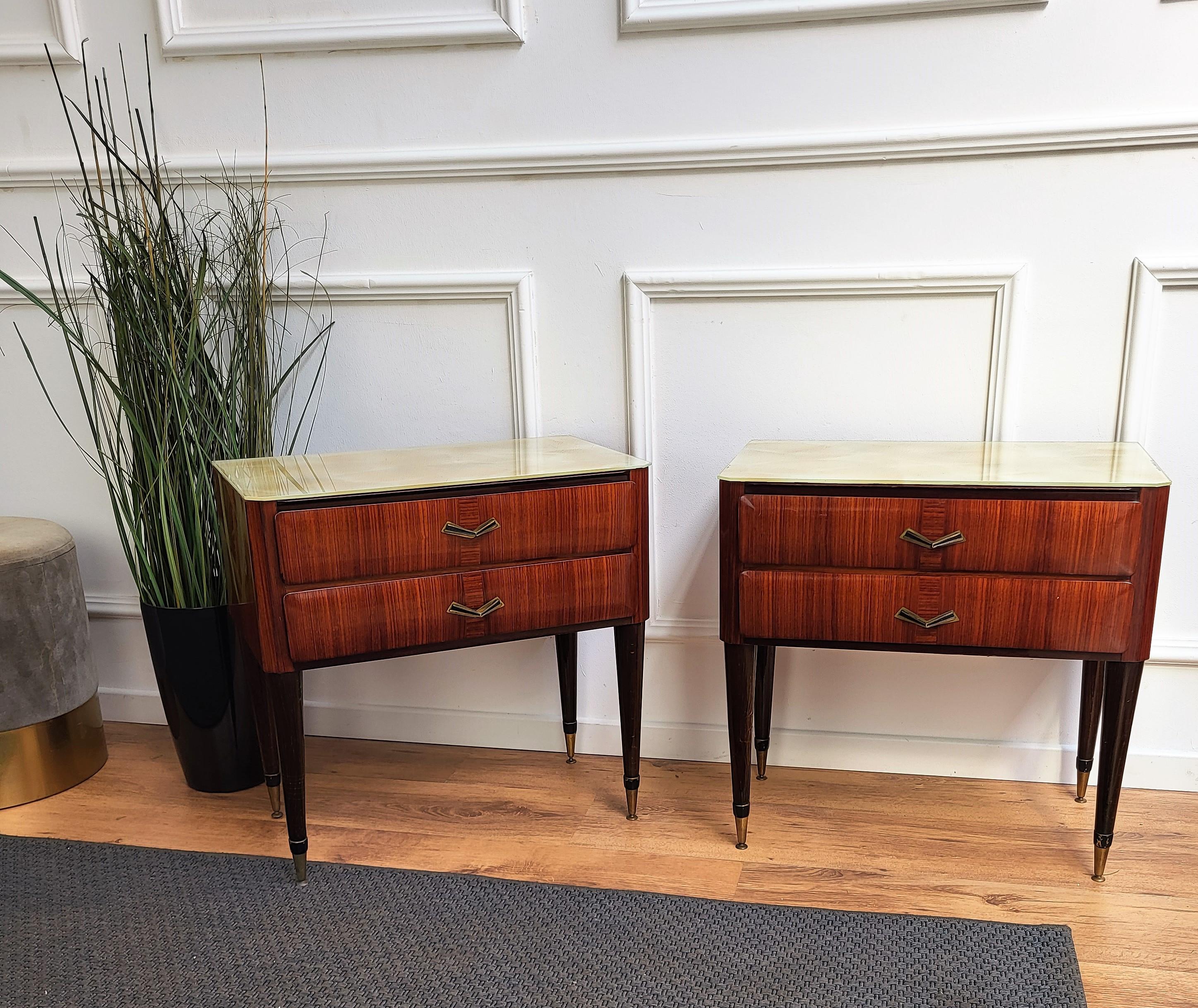 Very elegant and refined Italian 1950s neoclassical pair of bedside tables with double front drawers and great pattern design of the walnut veneer wood and lacquered glass top. Great details such as the brass handles make those nightstands a great