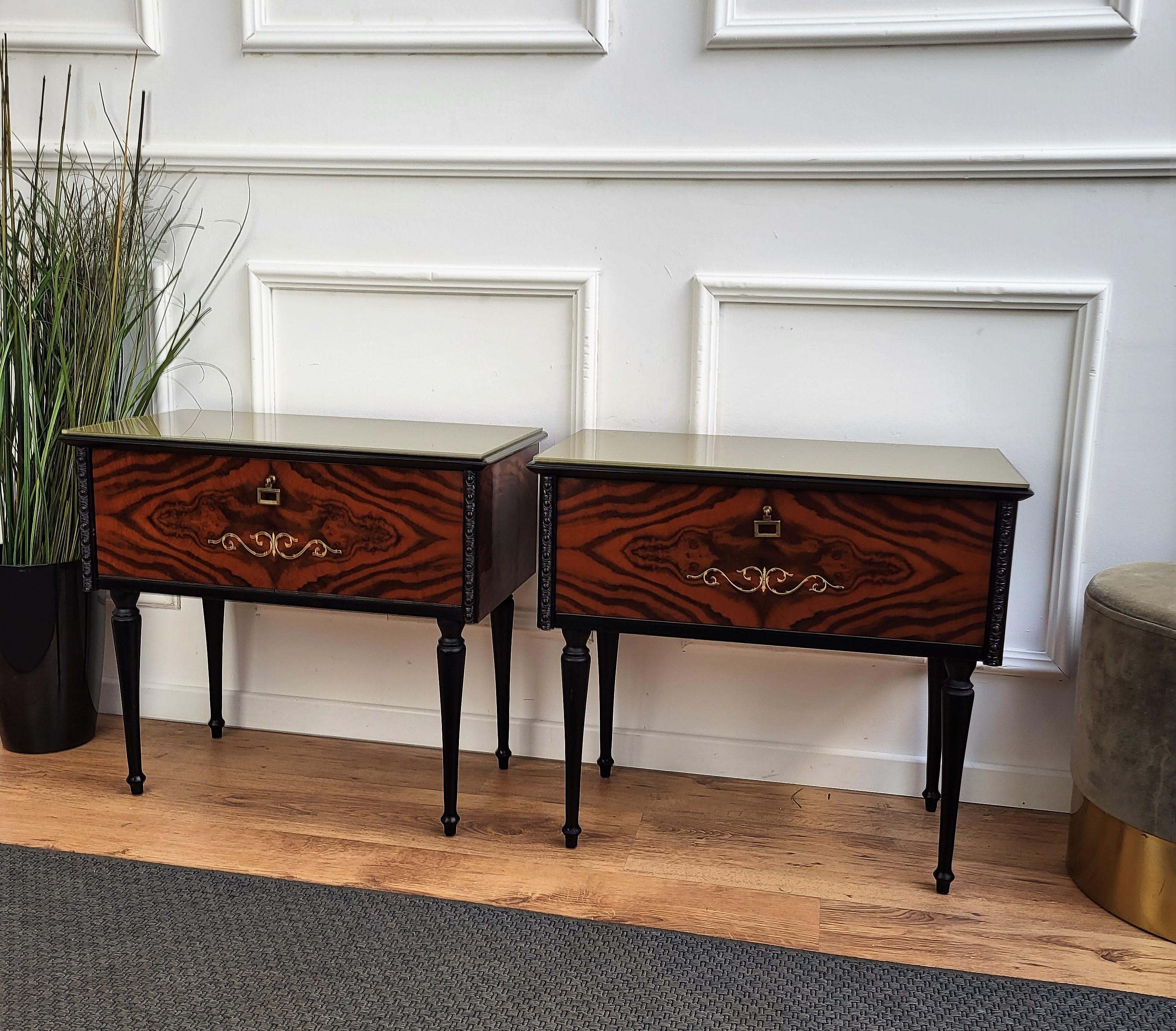 Very elegant and refined Italian 1950s neoclassical pair of bedside tables with front flip opening and great pattern design of the walnut veneer wood and lacquered glass top. Great details such as the brass handles make those nightstands a great