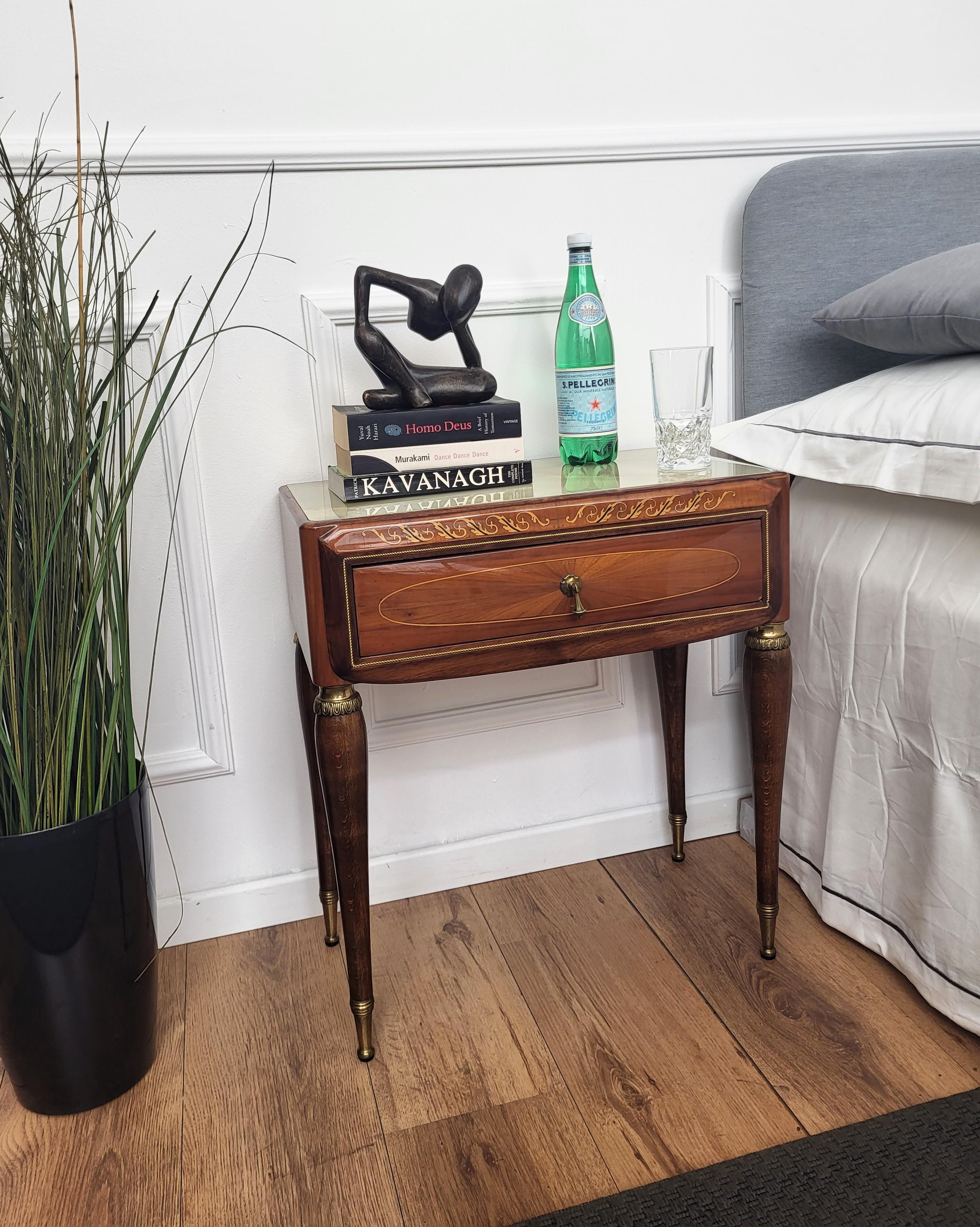 Very elegant and refined Italian 1950s neoclassical pair of bedside tables with inlay walnut veneer wood, drawer with brass handle, brown legs with brass final and lacquered glass top. Those nightstands make a great look in any style bedroom, as a