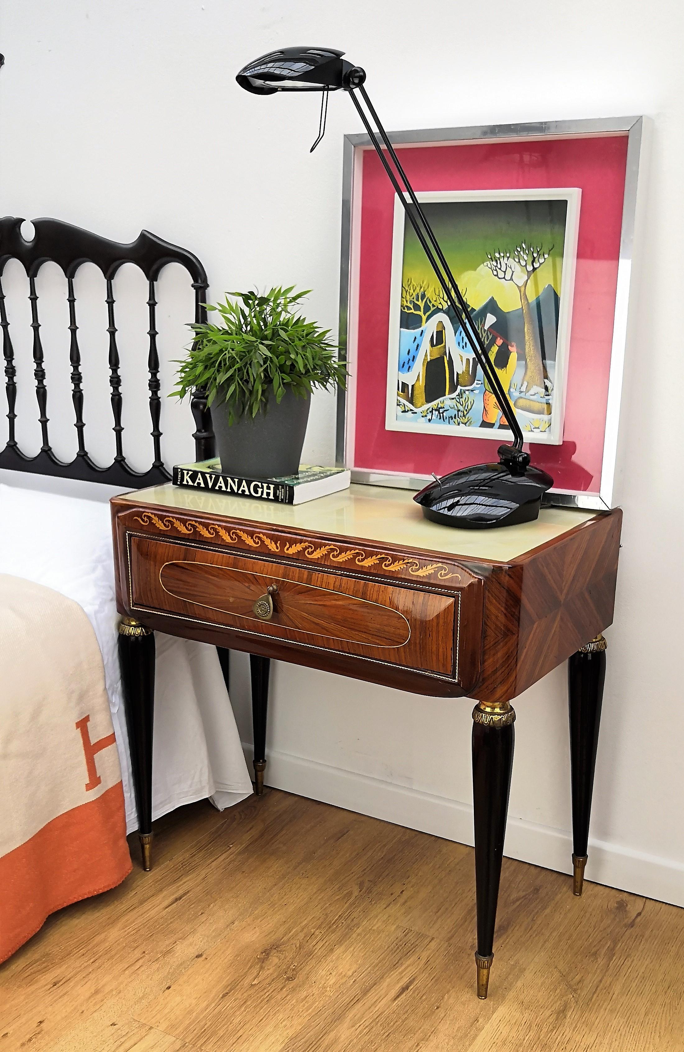 Very elegant and refined Italian 1950s neoclassical pair of bedside tables with inlay walnut veneer wood, drawer with brass handle, black legs with brass final and lacquered glass top. Those nightstands make a great look in any style bedroom, as a