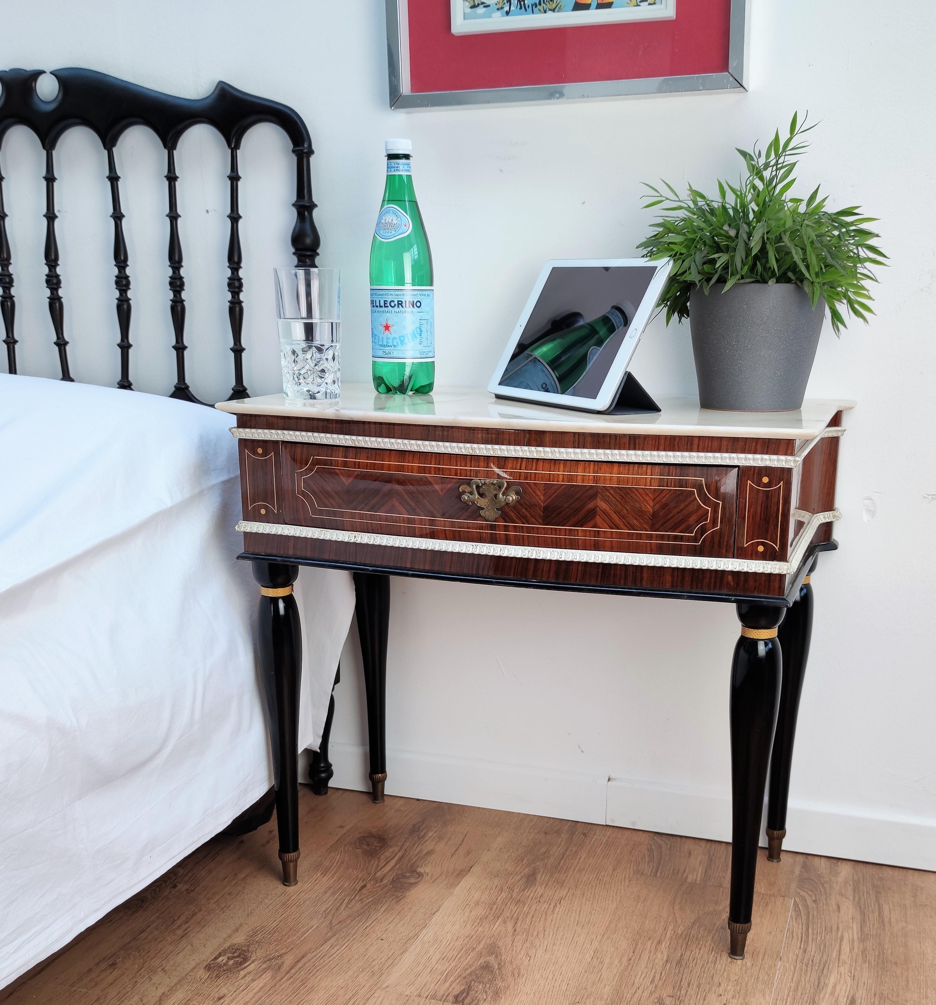 Very elegant and refined Italian 1950s neoclassical pair of bedside tables with inlay walnut veneer wood, drawer with brass handle, black legs with brass final and white marble top. Those nightstands make a great look in any style bedroom, as a