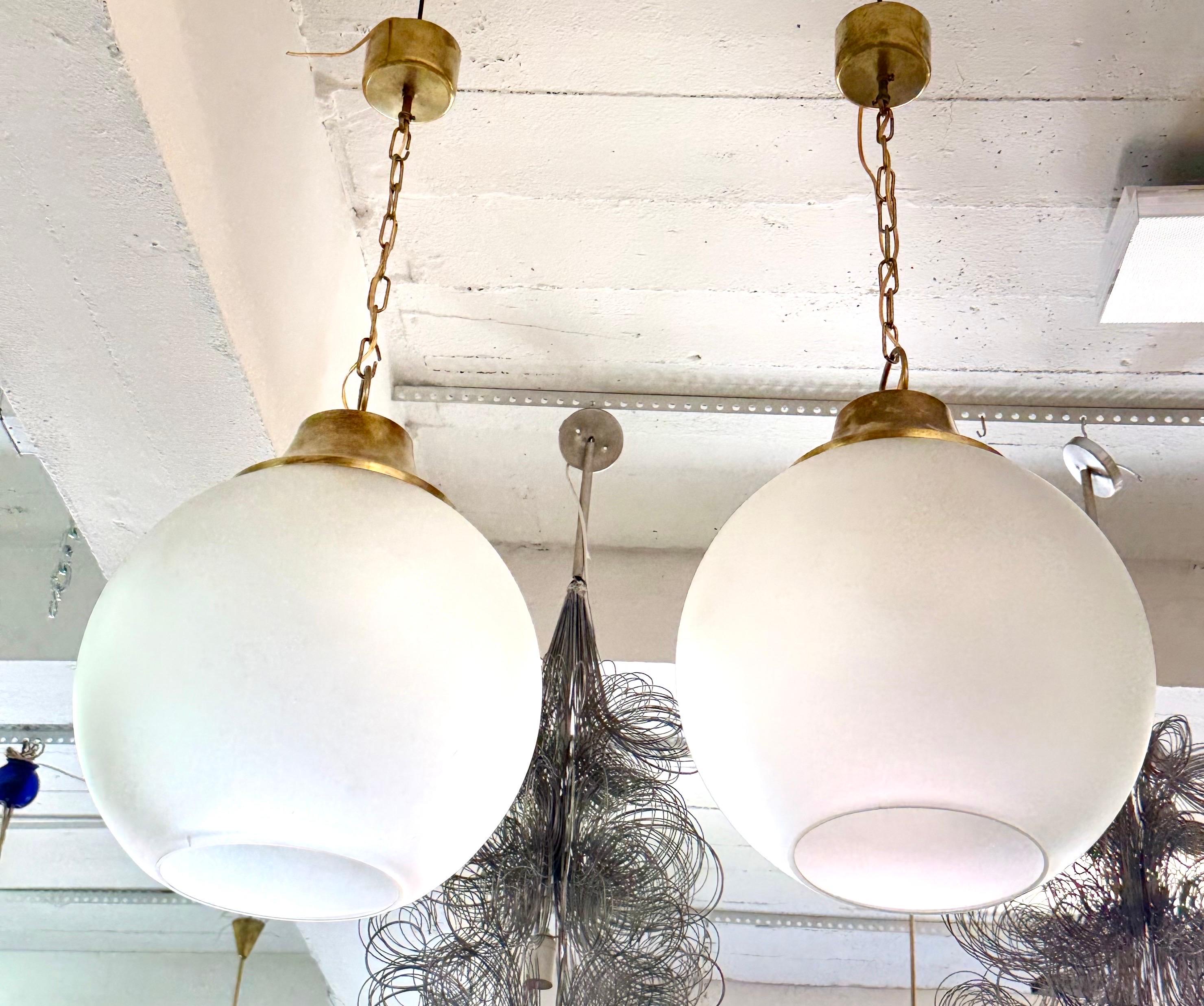 A Pair of Elegant, Sober Italian Mid-Century Modern frosted glass ball pendants / chandeliers/ lanterns by Italian Lighting Master of the 1960's, Luigi Caccia Dominioni. The lights are designed to light a room fully, evenly with beautiful forms.