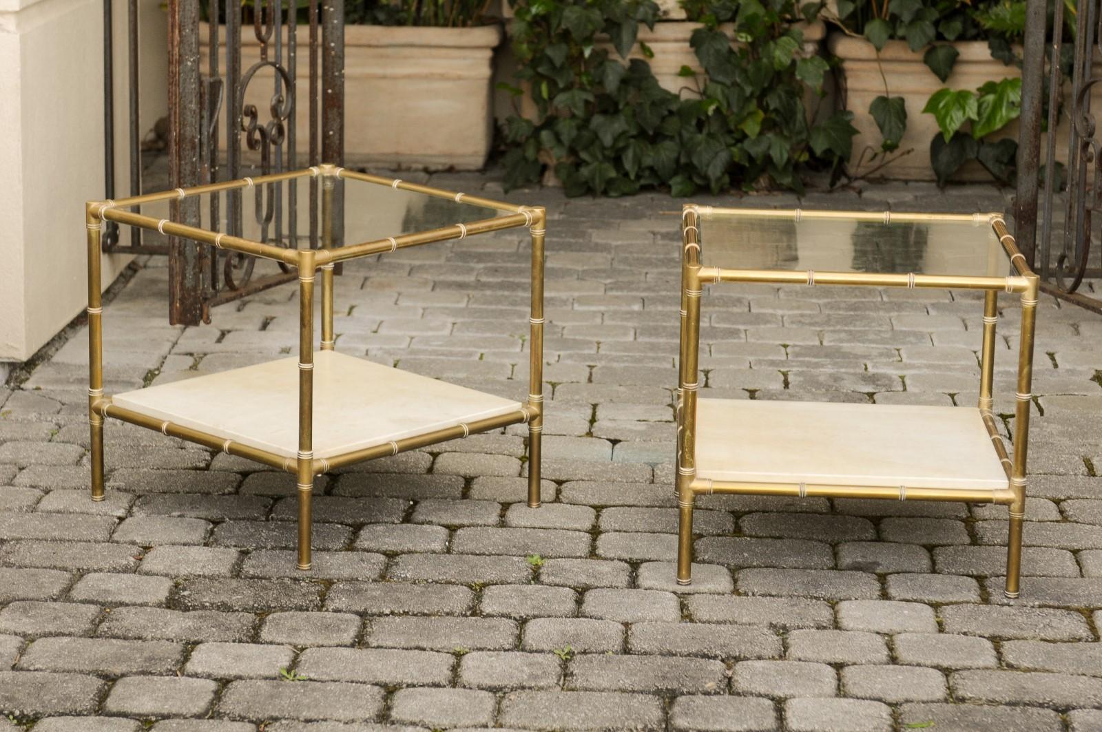 A pair of Italian brass side tables from the mid-20th century, with glass top and vellum shelf. Born in Italy during the midcentury period, each of this pair of stylish side tables features a brass bamboo-inspired structure, securing a glass top and