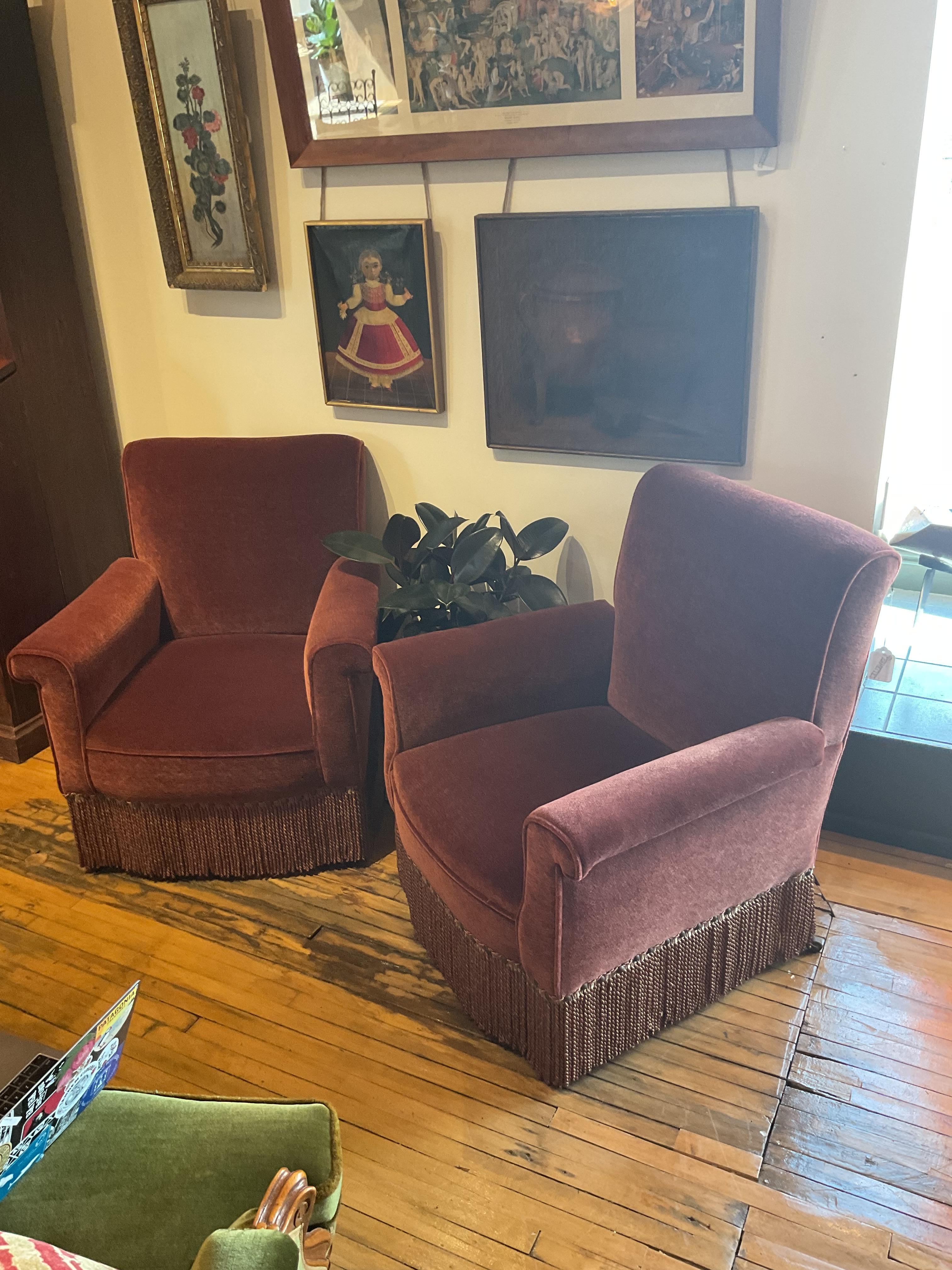 A richly upholstered pair of midcentury Italian club chairs, exuding vintage glamour and comfort in equal measure. These generously proportioned lounge chairs feature subtly flared, rolled arms and a high back, all wrapped in a plush burgundy velvet