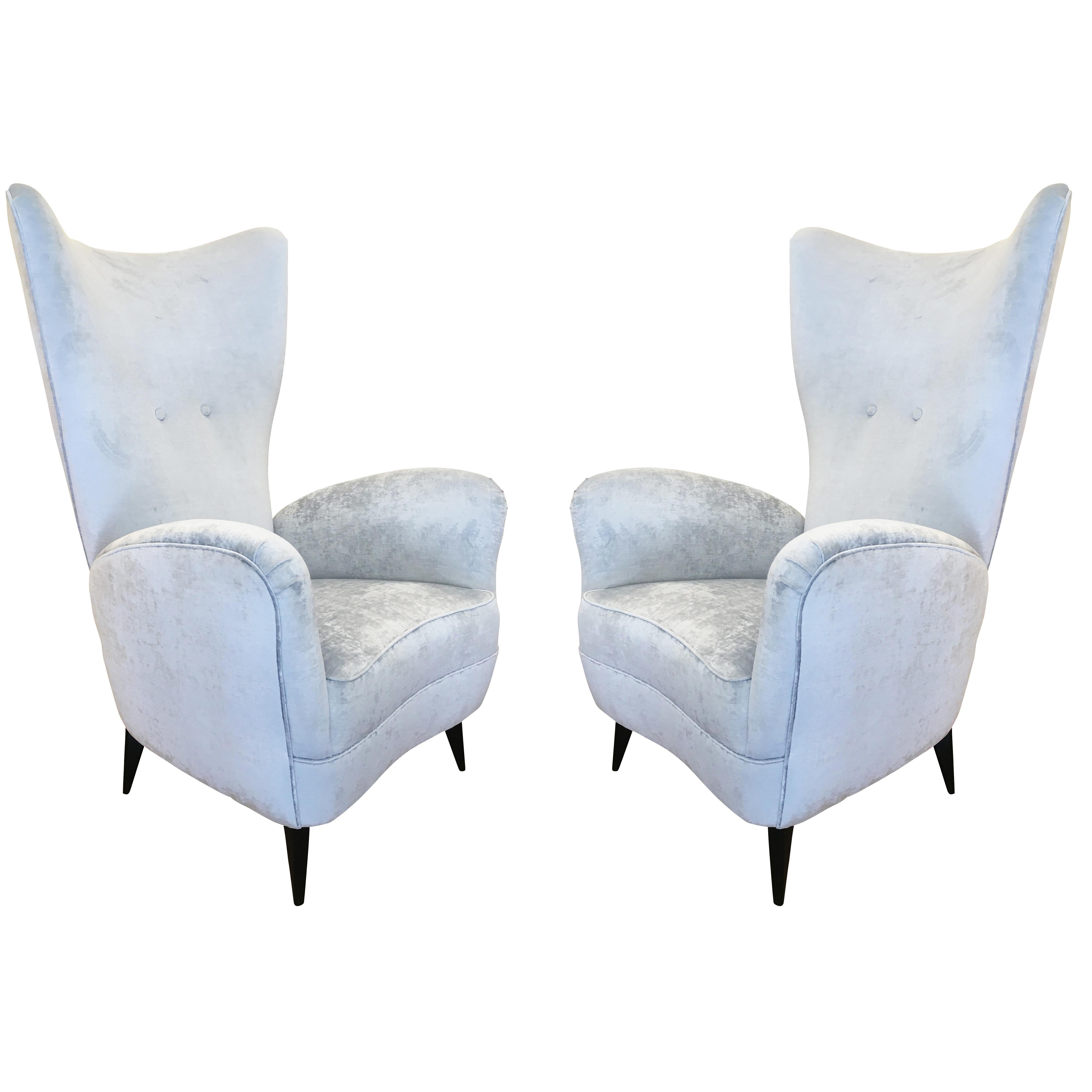 Pair of elegant 1950s lounge chairs with high backs and tapered wood feet. Beautiful curves define the sides and back. One has been upholstered with the fabric shown for display purposes and the other still has the original fabric.

Condition: