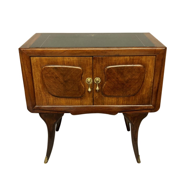 A pair of Italian Mid-Century night stands in walnut, with central cupboards, the original black glass tops and brass fittings.