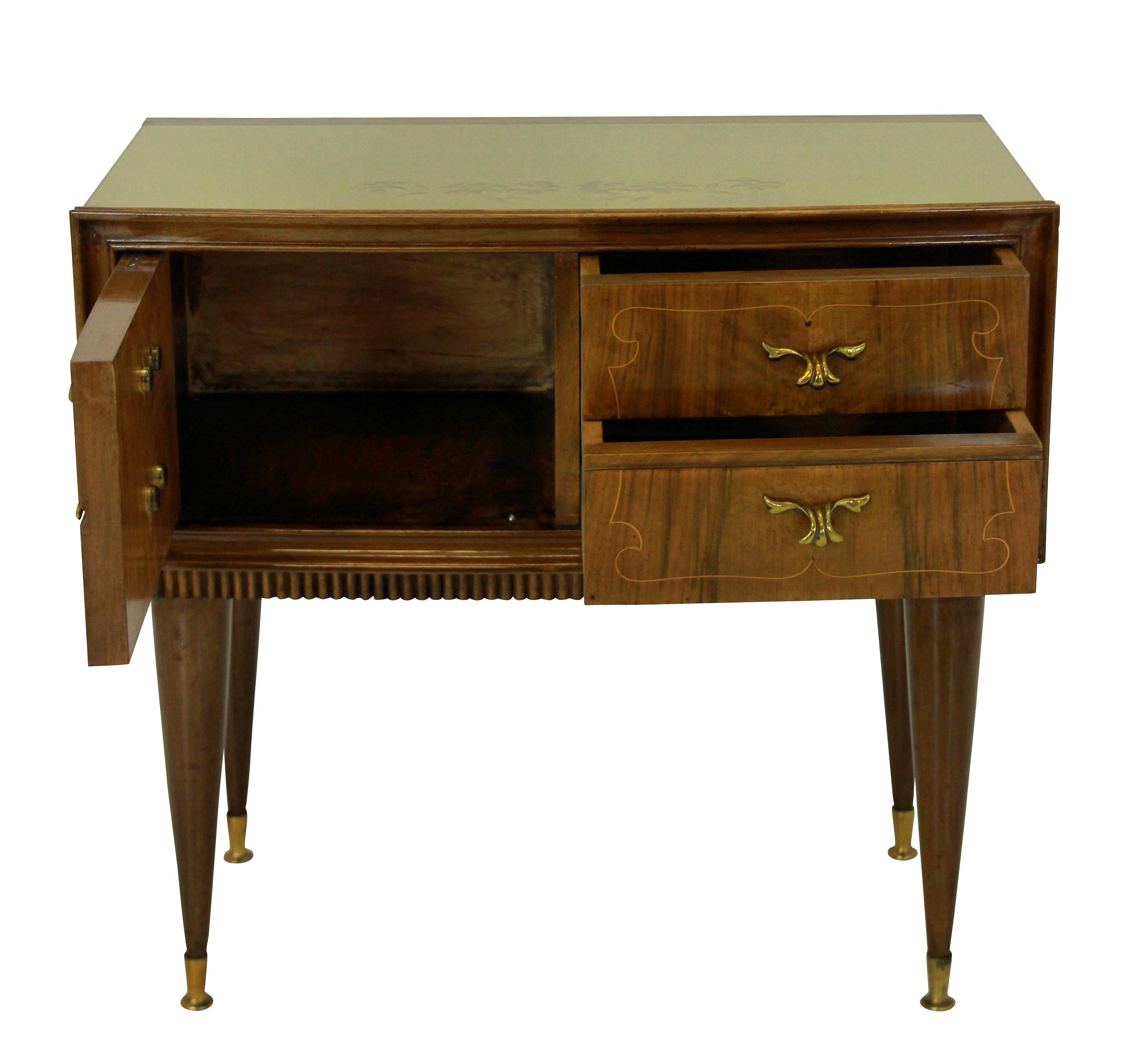 A pair of Italian midcentury nightstands in walnut, with figuring. Each having two drawers and a cupboard, with the original glass tops and brass fittings.
      