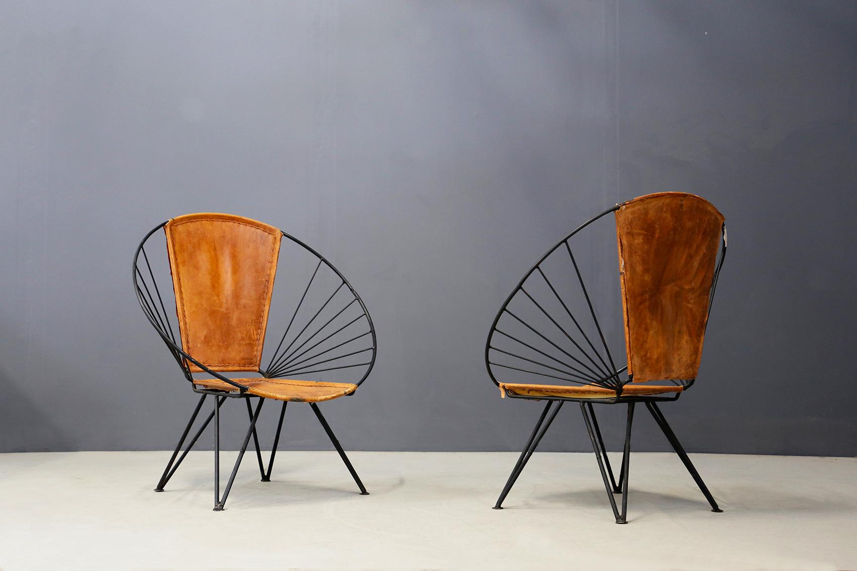 Pair of Italian manufacture oval armchairs in iron and leather, 1960s. The armchairs are made of a tubular iron frame. The seat and backrest are upholstered in a beautiful cognac-colored leather. The structure of the chairs is oval, almost