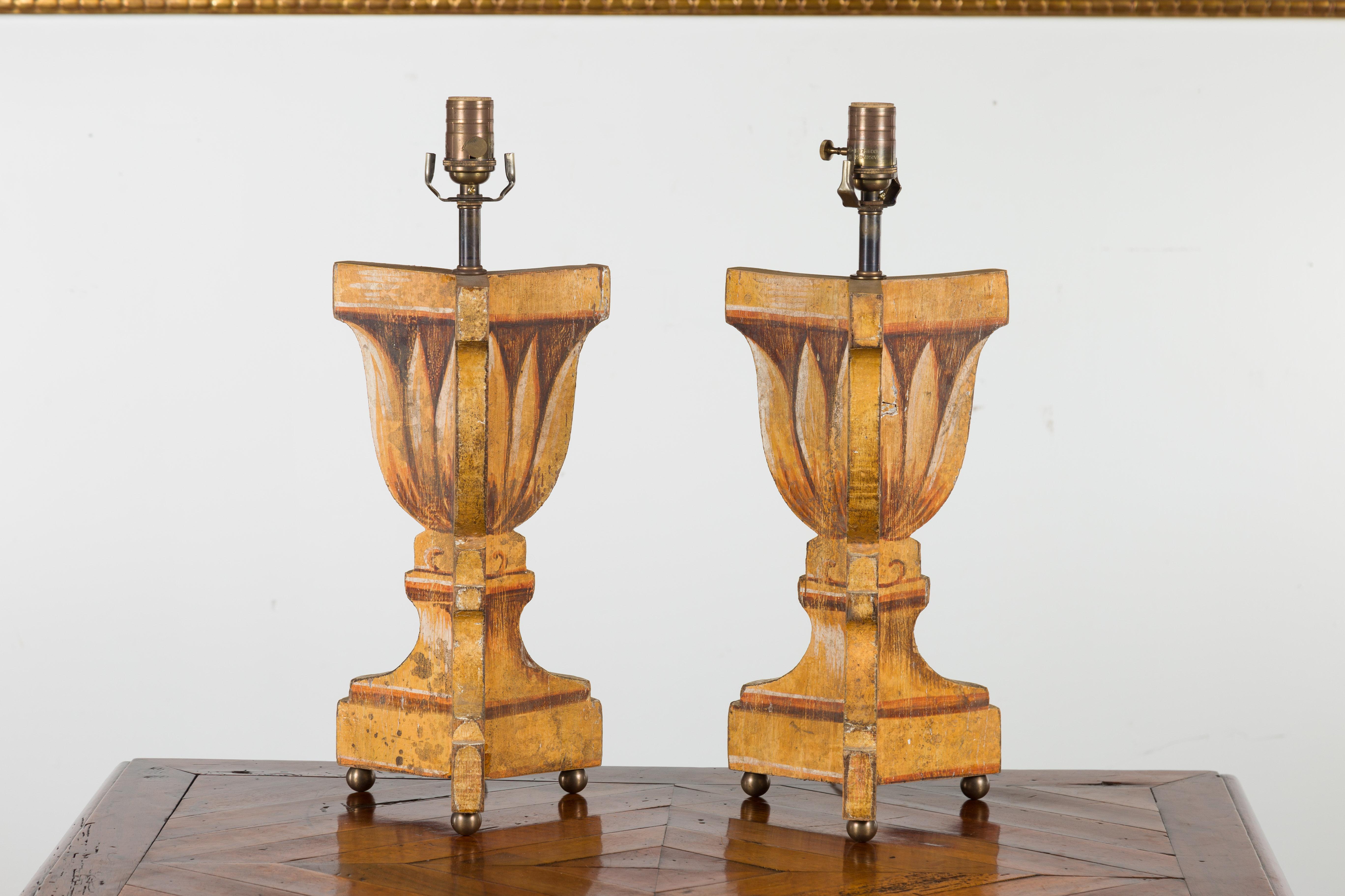 A pair of Italian vintage painted and carved table lamps from the mid-20th century, with stylized foliage decor and petite ball feet. Created in Italy during the midcentury period, each of this pair of table lamps features a painted decor depicting