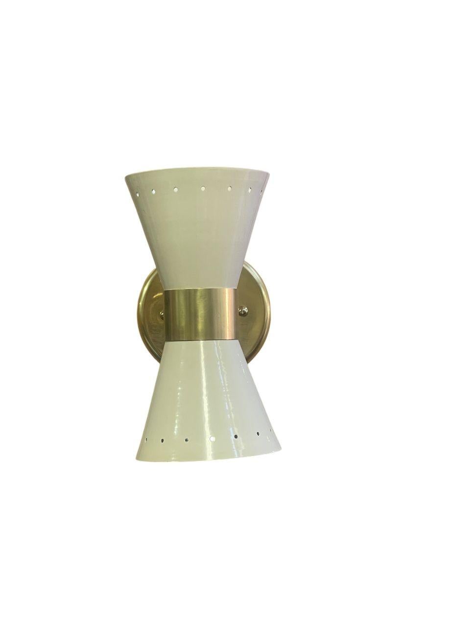 Une paire raffinée d'appliques italiennes du milieu du siècle, accompagnée d'une suspension assortie, présentant des abat-jours en métal émaillé élégamment montés sur des luminaires en laiton poli dans le style de Stilnovo. Ces pièces d'éclairage