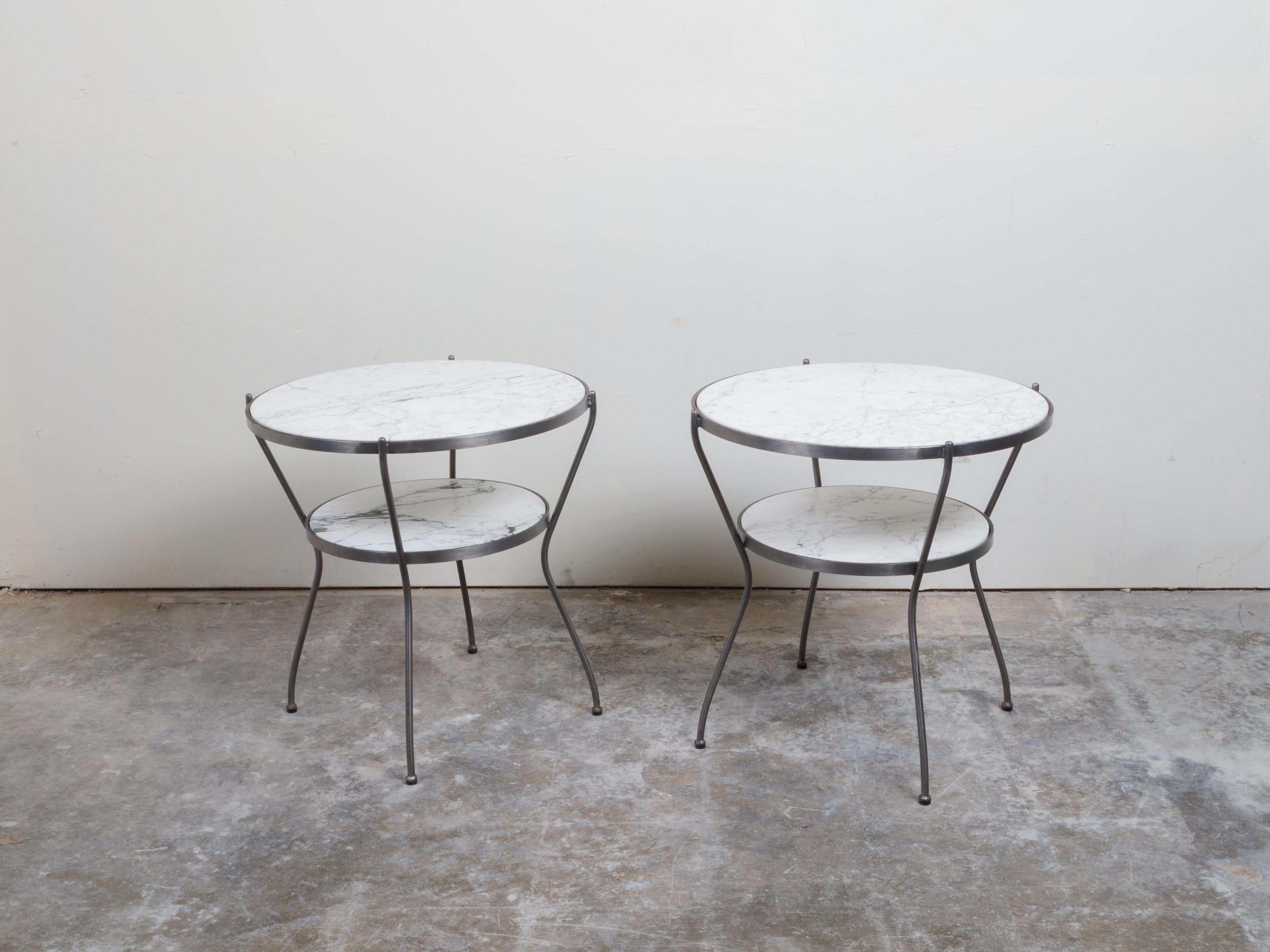 A pair of Italian steel side tables from the mid 20th century, with marble tops and shelves. Created in Italy during the midcentury period, each of this pair of side tables features a circular white veined marble top sitting above a smaller shelf of
