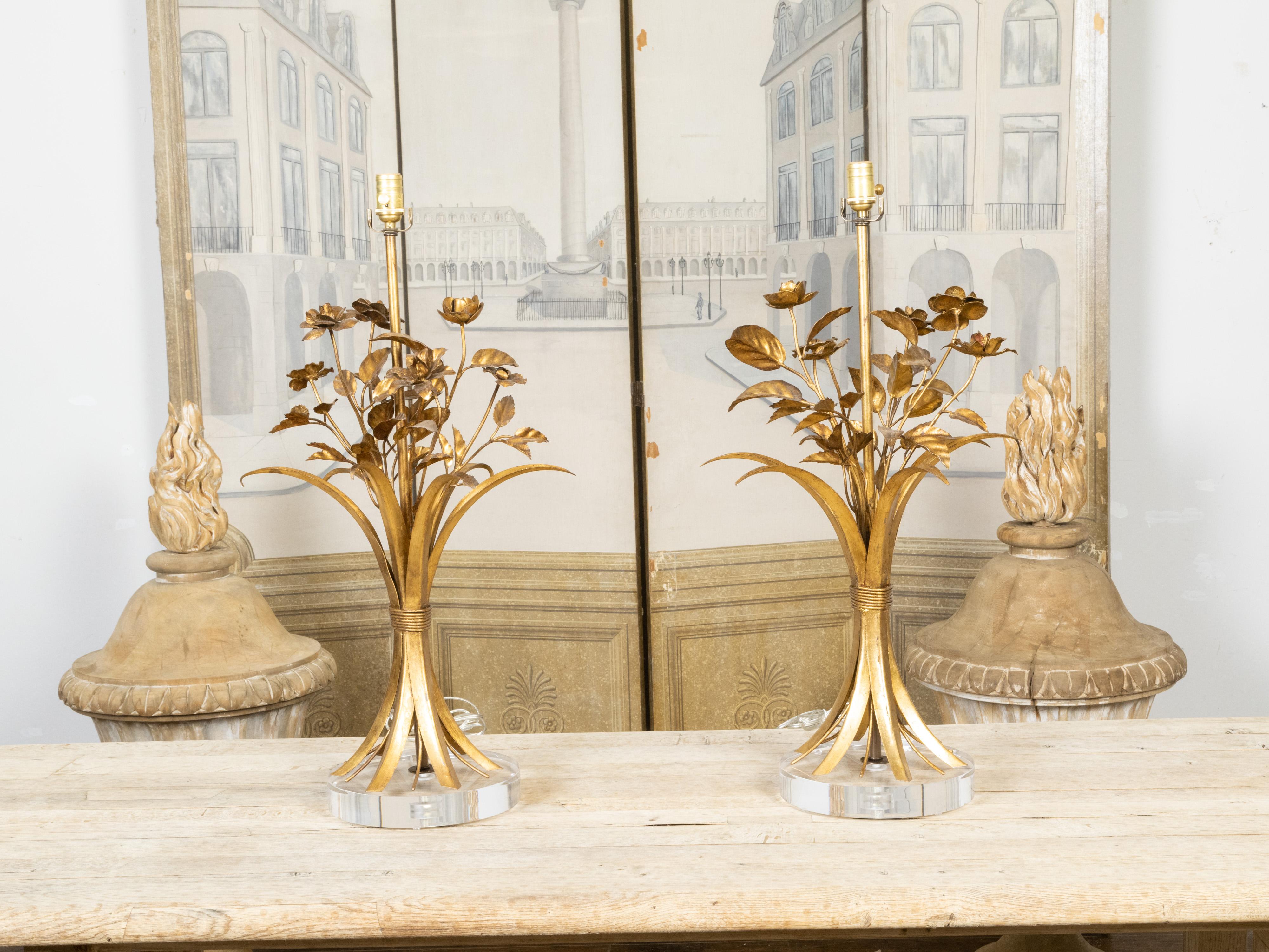 A pair of vintage Italian gilt metal table lamps from the mid 20th century depicting bouquets of flowers inside large leaves and mounted on round lucite bases. This pair has been professionally rewired for the USA and is ready to be plugged. Created