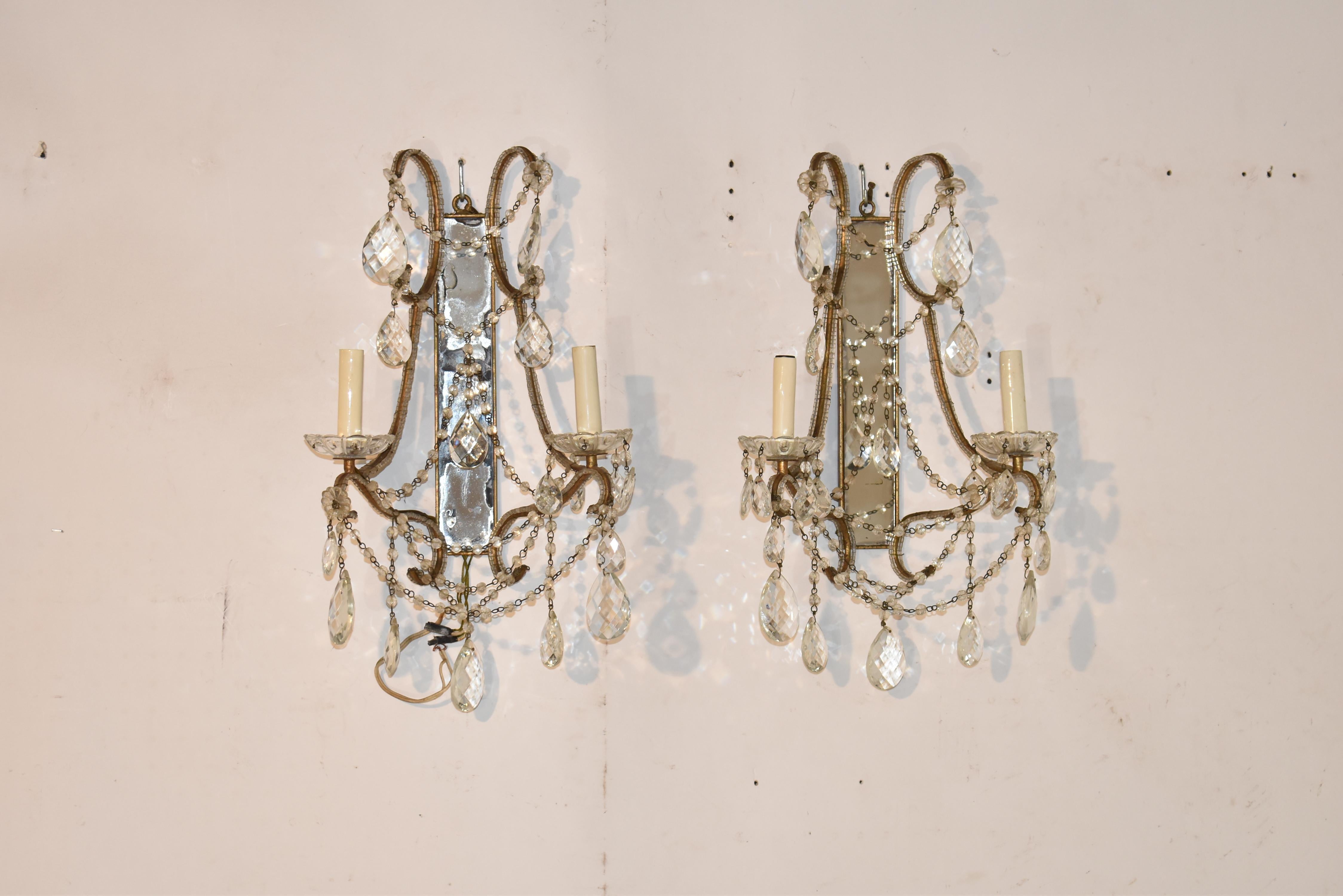 Wunderschönes Paar verspiegelter Wandleuchter mit zwei Armen, die durch anmutige Glasperlenketten verbunden sind und mit hängenden, facettierten Kristalltropfen verziert sind.  Die beiden Arme mit jeweils einer einzelnen Kerze ruhen auf Glasbögen. 