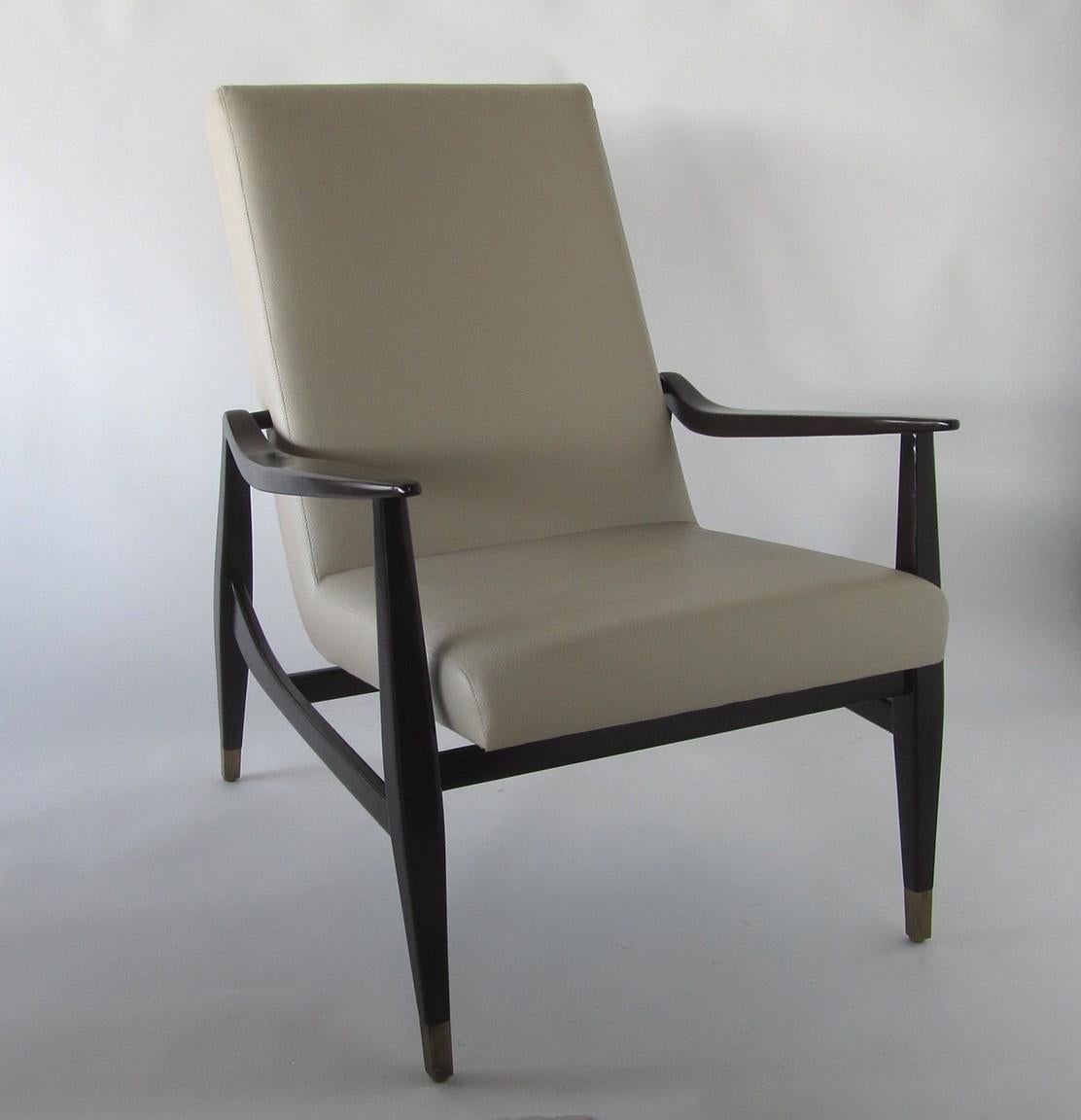 The frame with high back and flared arms and legs, joined by a stretcher. The legs terminating in brass sabots. Two sets available. 4 chairs available.