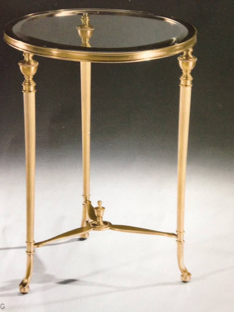 Two elegant Italian Mid-Century style modern neoclassical end tables, gueridons or nightstands in the style of Maison Jansen in antiqued solid brass with clear beveled glass tops. These Regency style tables feature urn decoration and tapered legs.