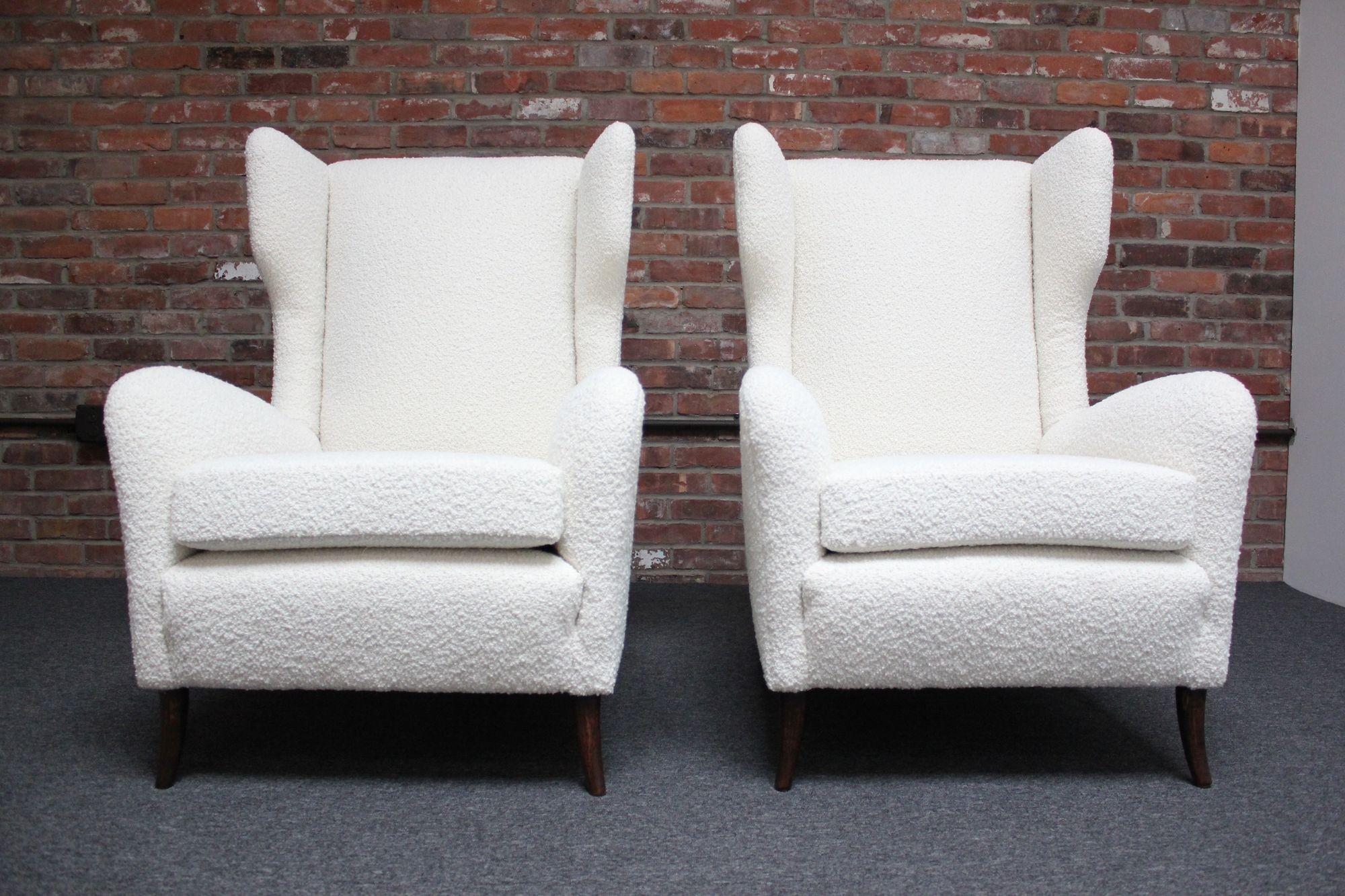 Modernist wingback chairs supported by sculptural, walnut feet (circa 1950s, Italy).
Stylish design, without compromising function and comfort.
Luxurious pair newly reupholstered in a cream Kravet bouclé 36120-1). The foam has additionally been