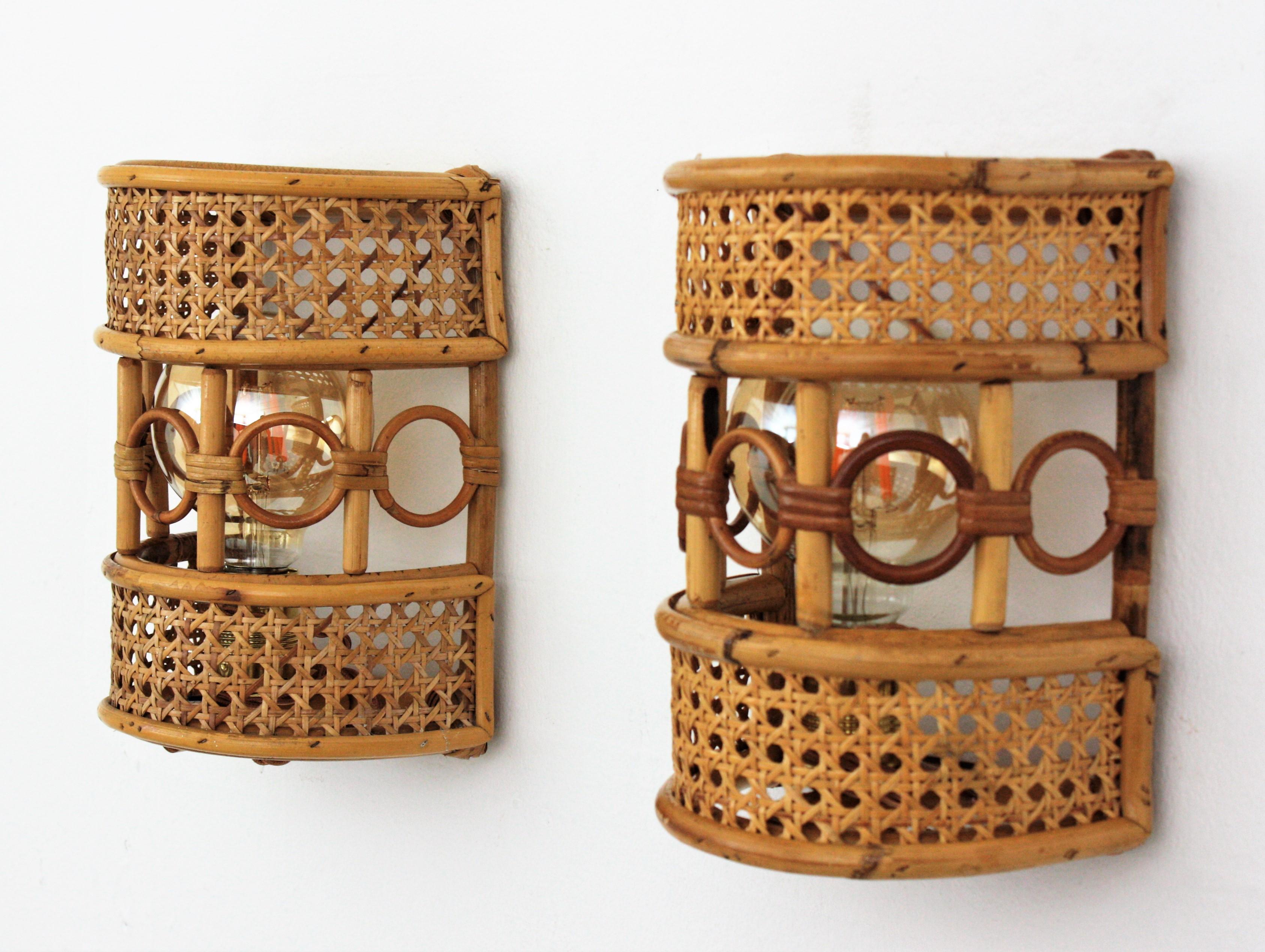 Pair of half cylinder wall lights with wicker / rattan woven shades accented by rattan circles. Italy, 1960s.
These light fixtures are made with wicker basket weave panels on a rattan semi cylindrical structure. They have a beautiful decoration