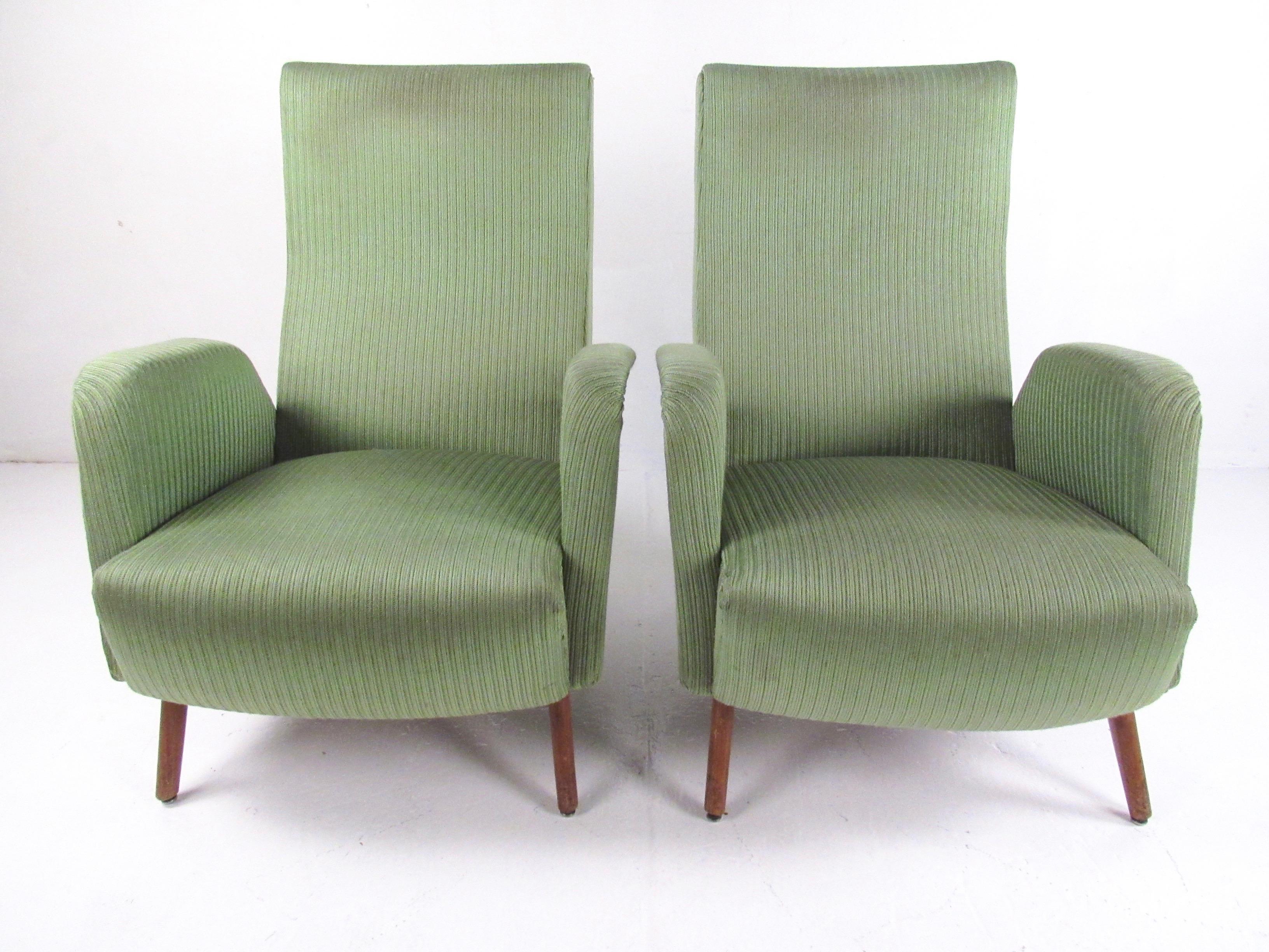 This striking pair of Mid-Century Modern Italian lounge chairs feature vintage fabric, sculpted high back seats, and upholstered arm rests. Vintage brass upholstery studs showcase the 1950s Italian modern sensibility while the hardwood construction