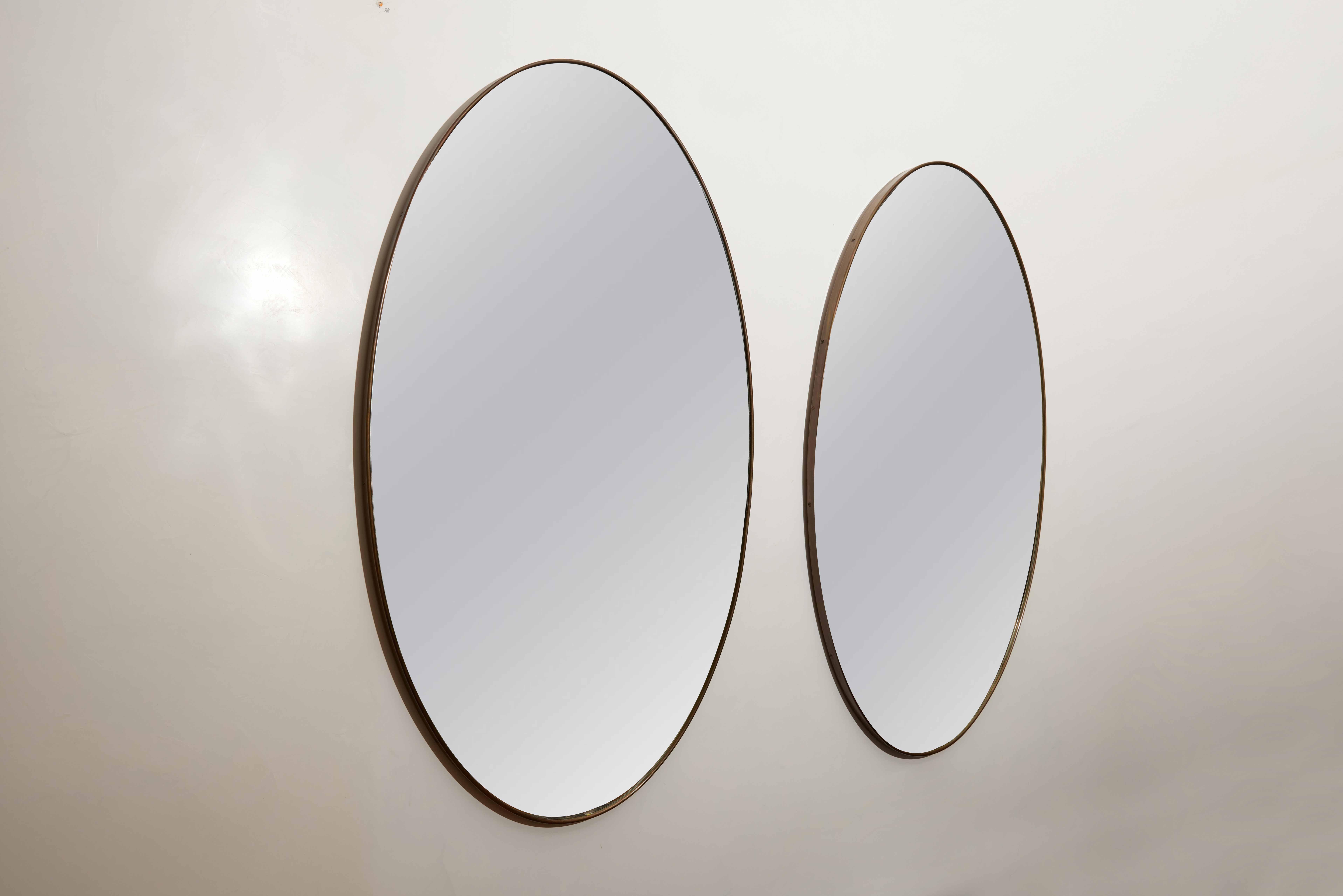 Pair of Italian Modernist Brass Oval Wall Mirrors, Italy, circa 1950

This pair of Italian Modernist oval brass mirrors offers a grand scale that brings both light and depth to any interior space. Crafted in Italy around the 1950s, these mirrors are