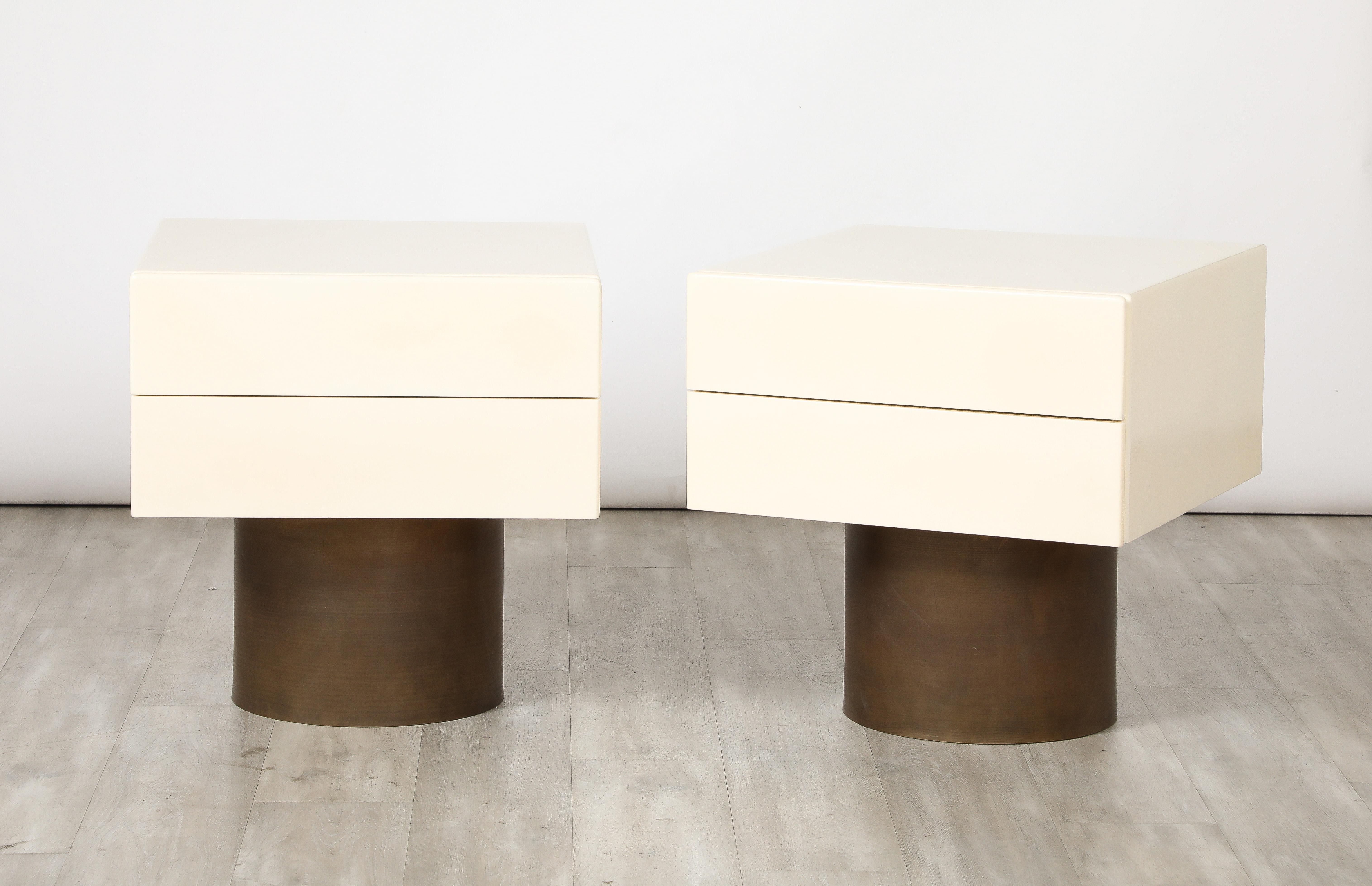 A pair of Italian modernist lacquered bedside / end / side tables, of wonderfully geometric form with a square shaped two drawer cabinet supported on a cylindrical metal base.  A sleek piece with great contrast of materials and form. 
Italy, circa