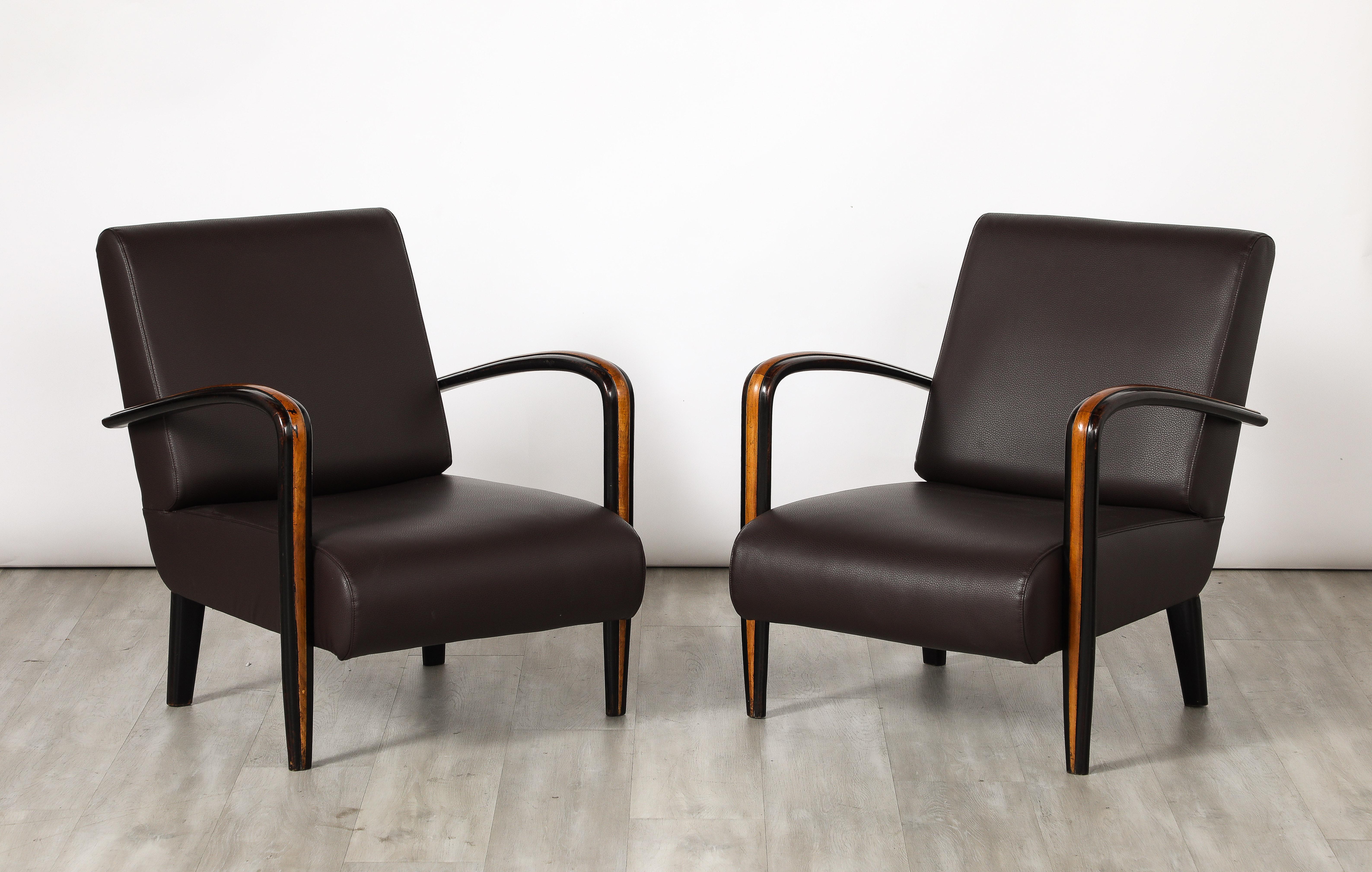 A pair of Italian Art Deco lounge chairs with elegantly sloped arms carved in walnut with a contrasting fruitwood inlay.  Newly re-upholstered in a chocolate brown Italian leather.  A striking and sophisticated design; so indicative of the Art Deco