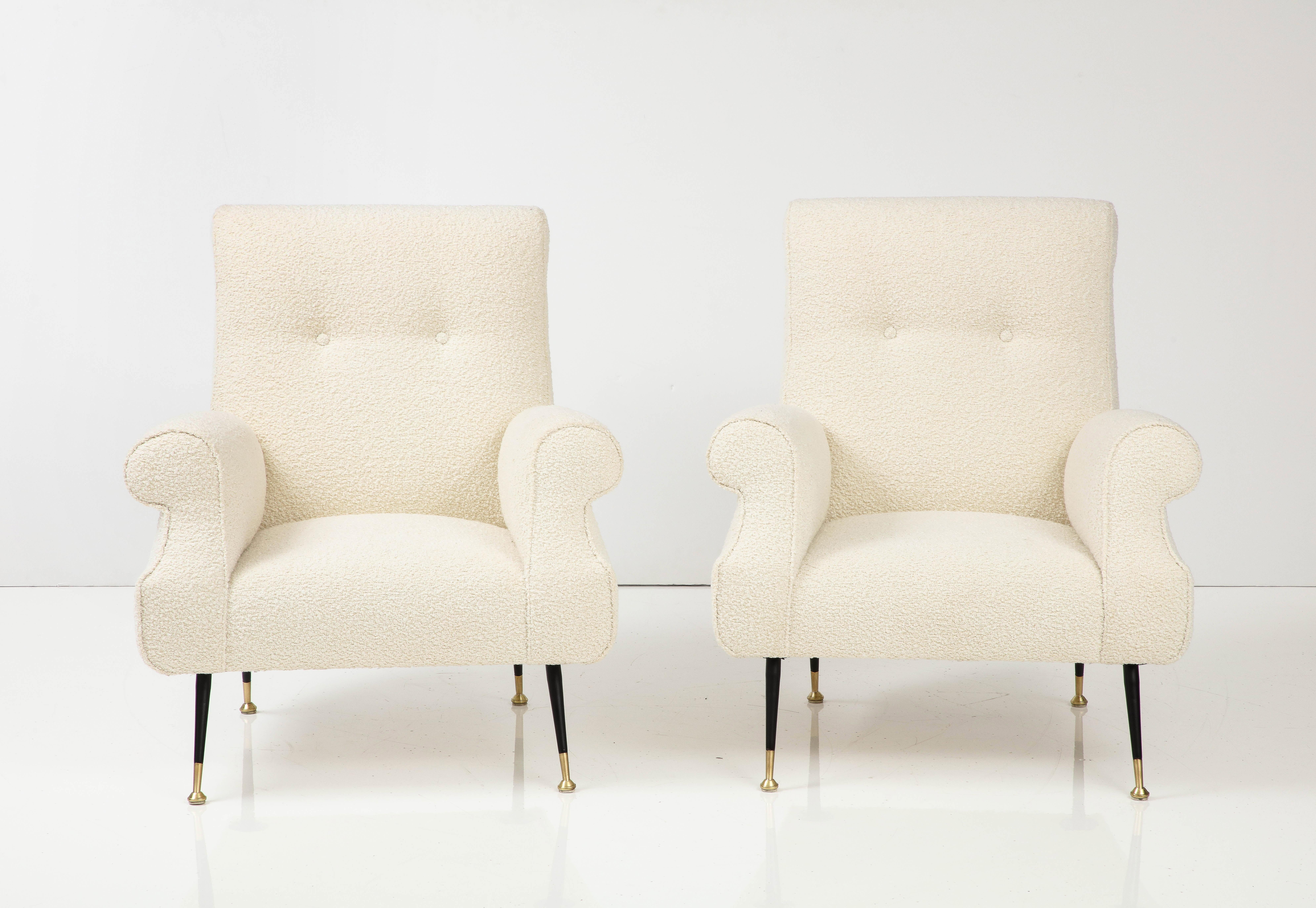 A pair of grand scale Italian modernist lounge chairs with great sculptural form, the large and comfortable seat supported on elegantly appointed black metal and brass tapered legs.  Newly re-upholstered in a creamy textured European boucle fabric. 