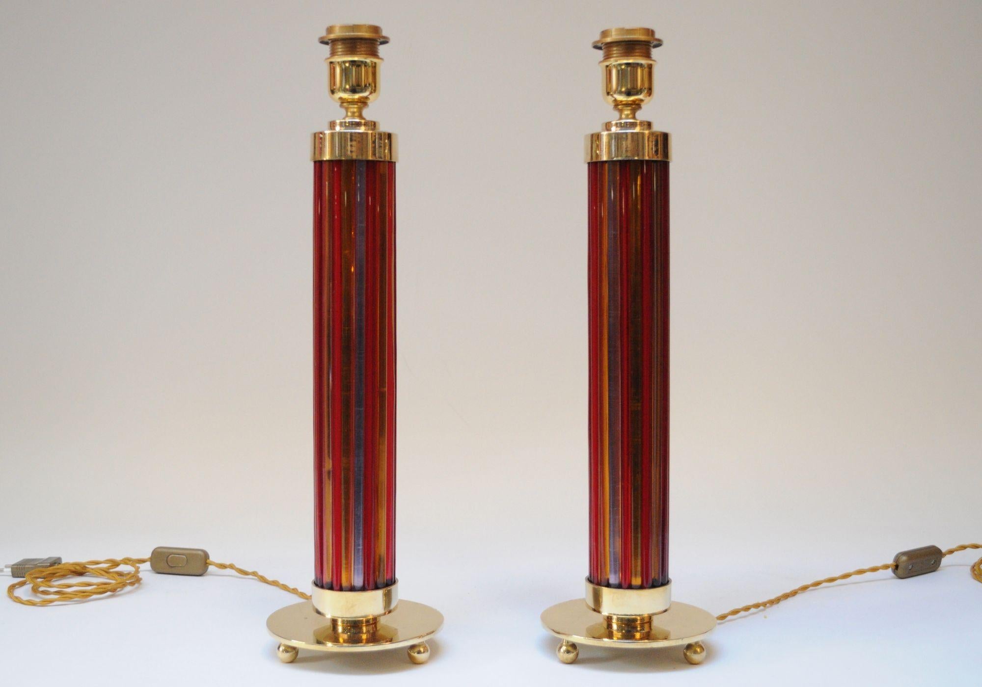 Bunte, elegante Murano-Tischlampe (ca. 1950er Jahre, Italien).
Besteht aus einzelnen Murano-Glassäulen in Orange, Rot und Violett, die Säulen bilden und oben und unten von Messingkappen und einem Sockel mit drei Kugeln getragen werden.
Die Blasen