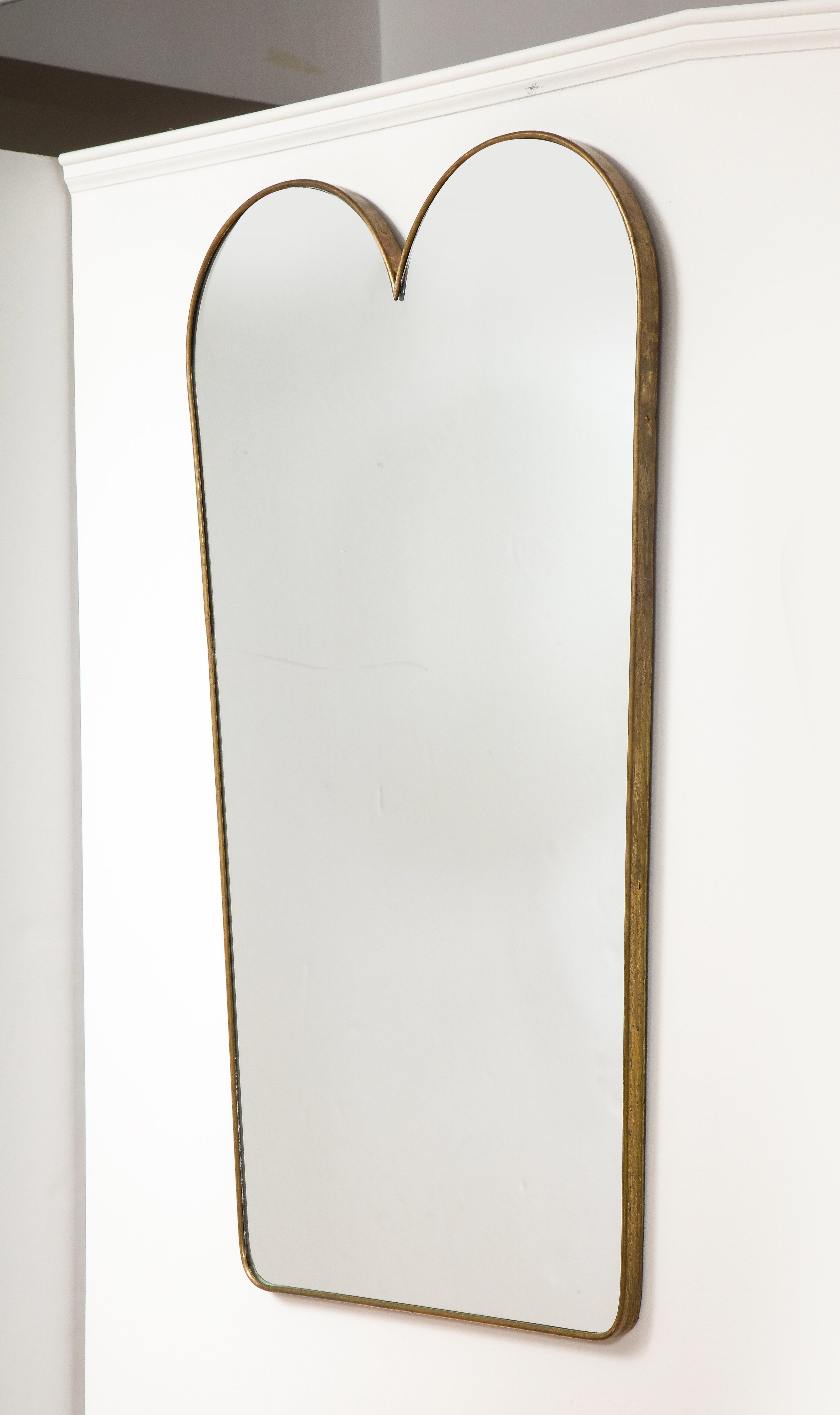 An elegant pair of Italian 1950's brass modernist mirrors with a scalloped shaped designed crest. Made with excellent craftsmanship and solid construction, with solid wood backing. This pair of mirrors offers clean modernist lines and of organic