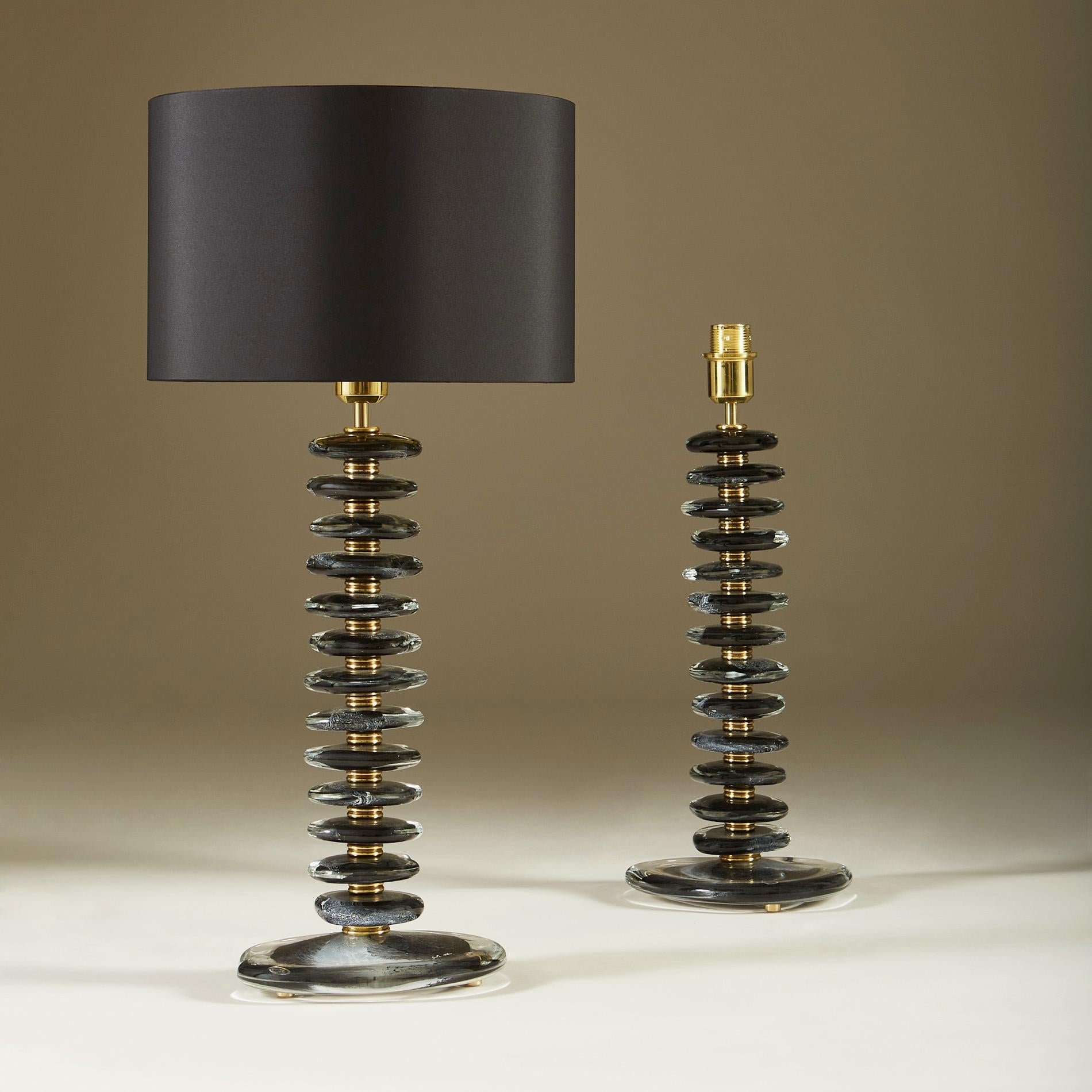 Importante paire de lampes de table contemporaines. Chaque lampe est composée de 12 galets sculptés lisses faits à la main, de couleur noire avec des détails clairs et blancs. Chaque galet est entrecoupé de sections de laiton à double nervure et
