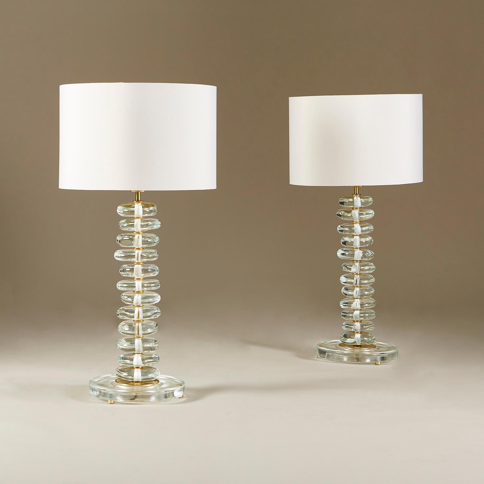 Tall contemporary table lamps composed of pillars of individually-shaped glass pebbles standing on circular glass bases with brass detailing.

The dimensions below are those of each lamp only. Measure: The shades are 10 inches high.