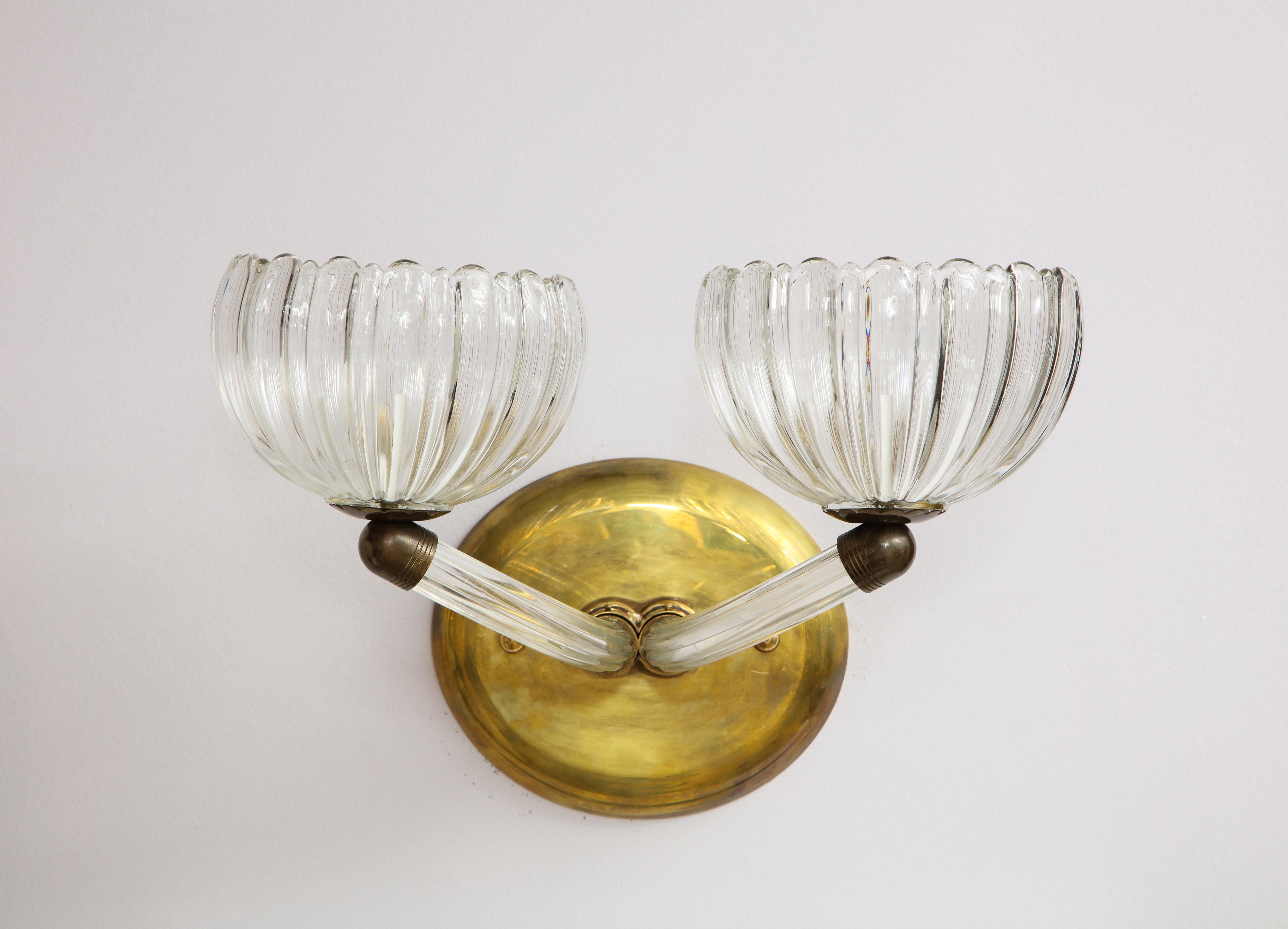 Pair of Italian Murano glass wall sconces with oval brass wall plaques; the molded glass with elegant scalloped design, each supported by upturned arms.
Italy, circa 1950 
Size: 17” wide x 12” deep / Plaque: 8” high x 9” wide.