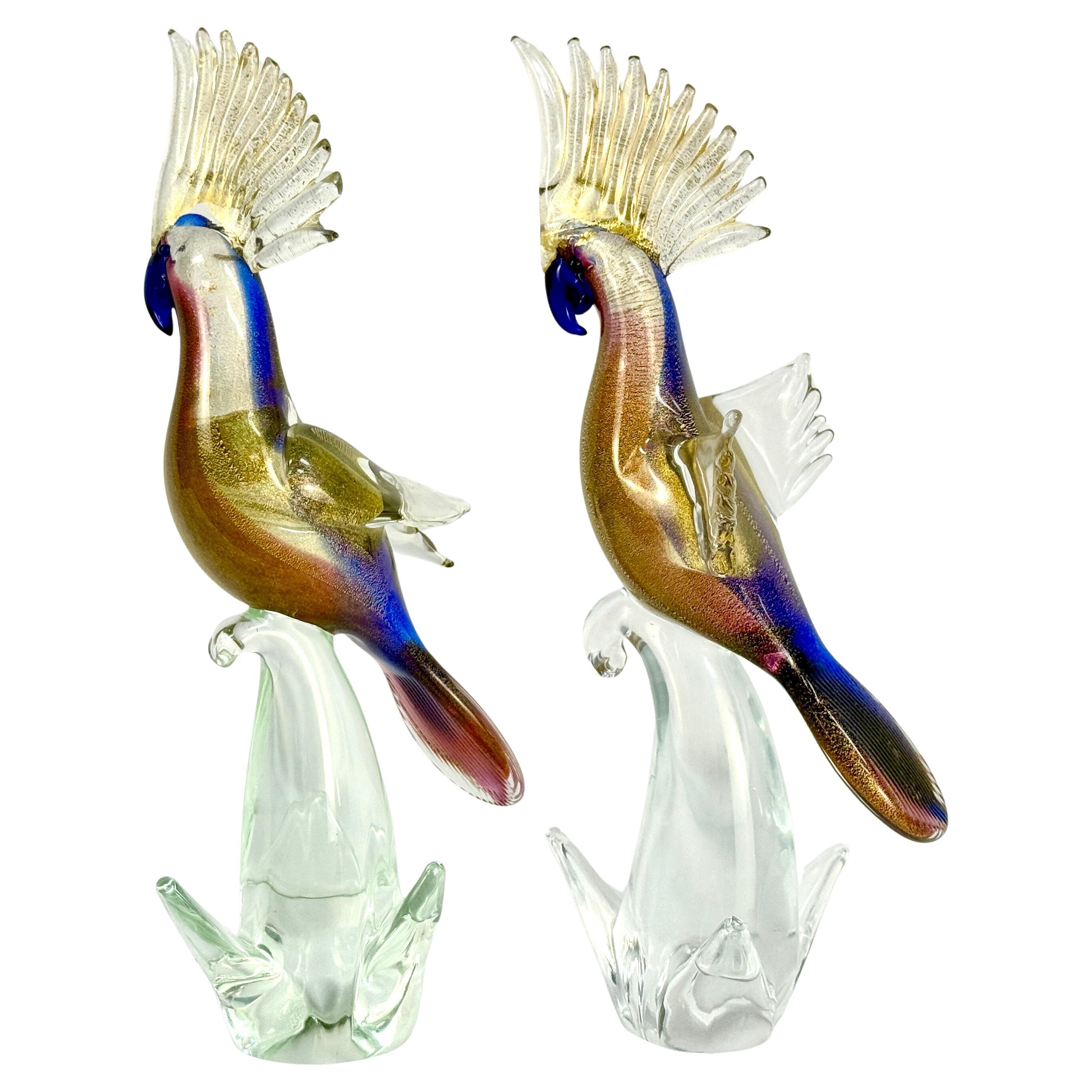 Paire de sculptures artisanales italiennes de Murano en forme de cockatiel, datant du milieu du 20e siècle. Les magnifiques sculptures sont d'un bleu cobalt vibrant avec des oiseaux légèrement teintés de rose, avec des mouchetures d'or, et reposent
