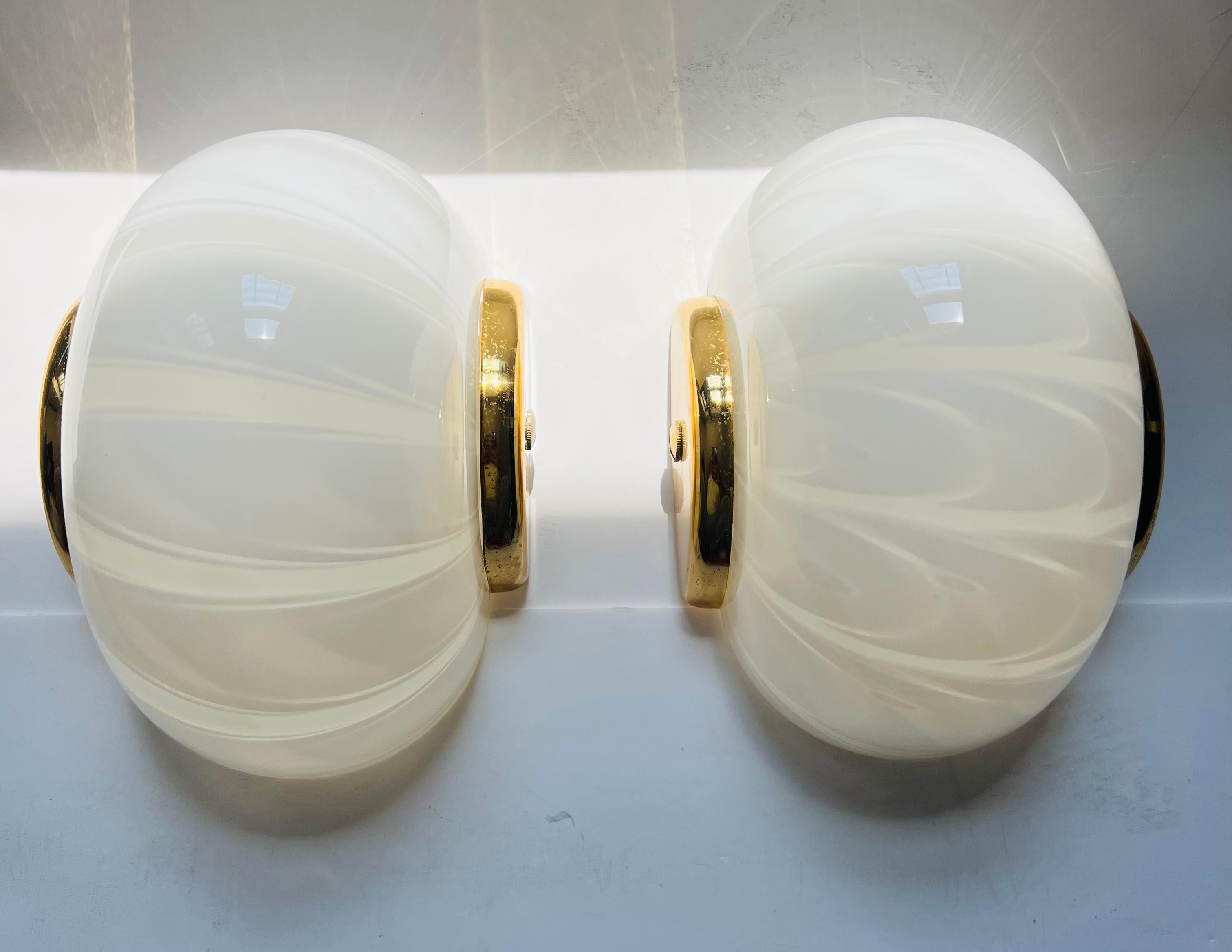 A pair of Italian 1970s egg shaped wall lamps in white and clear Murano glass with polished brass fittings. Made by the Italian light maker, Fabbian. Newly rewired. Can be hung vertical
Or horizontal.