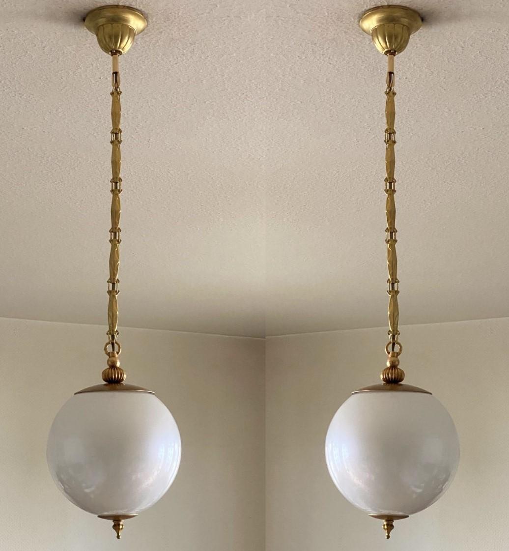 An elegant pair of Murano glass globe pendants in pearl optic, brass mounts, chain and canopy, Italy, 1960s. These beautiful and rare pendants look really like a big pearl hanging from the ceiling. With a single brass and porcelain Edison E27 light