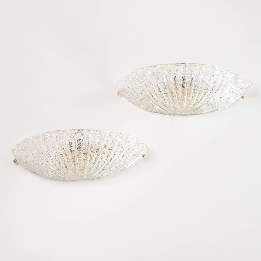 Beautiful pair of Italian Murano glass sconces. Fluted wide shell shape with ribbed detailing in glass and wavy glass detailing along top wedge. Brass screws on sides to attach glass to original brass backplate. Newly re-wired with single socket in