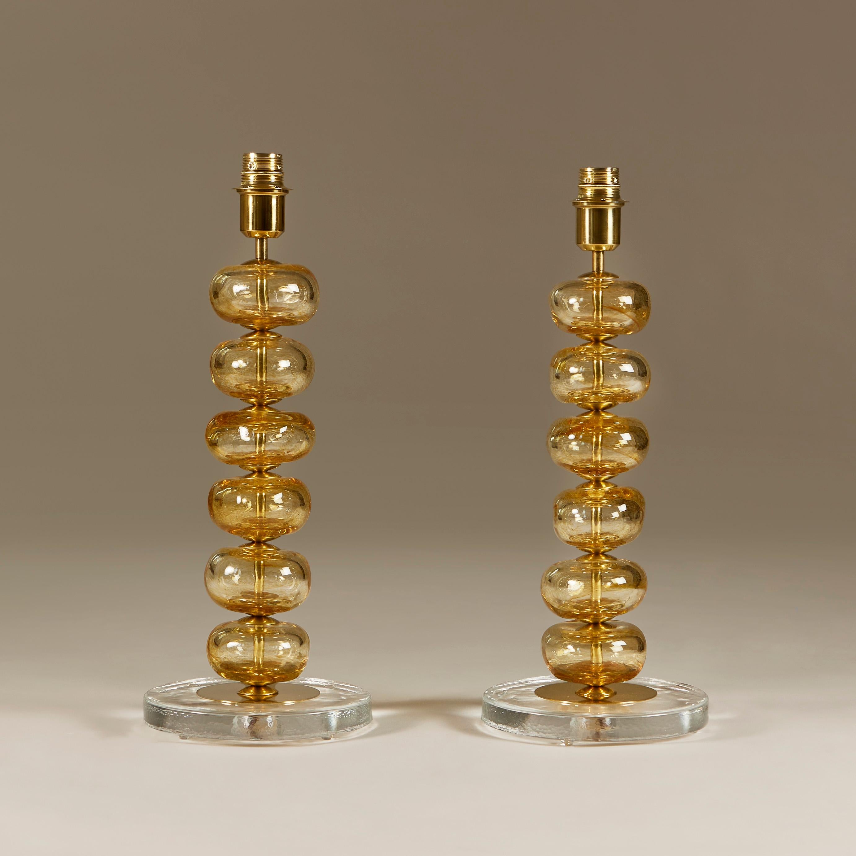 Elegant pair of table lamps each consisting of six handblown soft gold sculptured Murano glass disks interspersed with brass detailing. Sits on circular clear glass and brass base.

Due to the handmade nature of the glass no two pieces are exactly