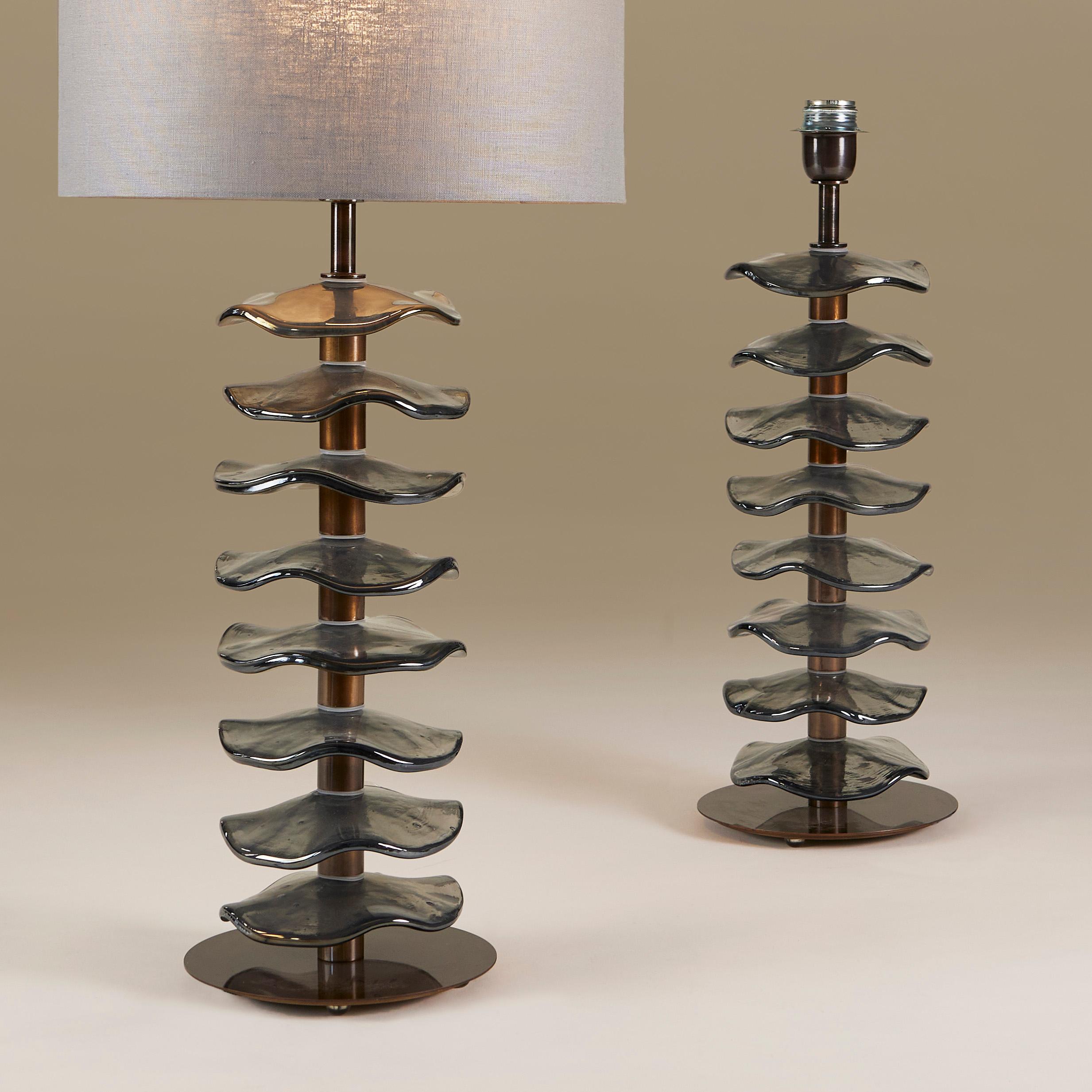 Imposing pair of chic table lamps consisting of eight individual handmade Murano pale grey petal disks with subtle iridescent sheen. Each sits on a dark brass stem with simple circular brass base.

Lampshades optional. 70cm high x 35cm diameter with