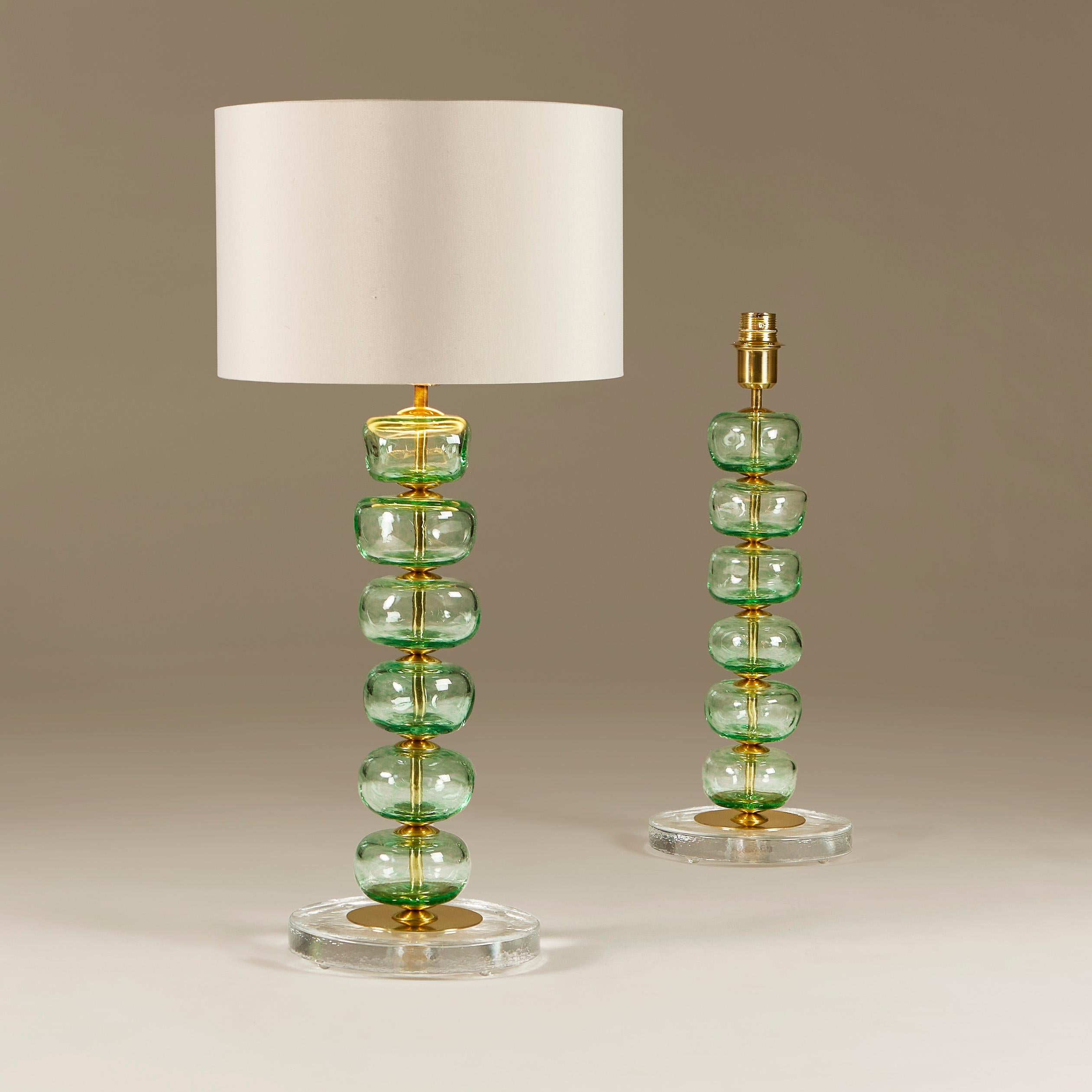 Élégante paire de lampes de table composées chacune de six disques en verre de Murano soufflé à la main et sculpté en vert tendre, entrecoupés de détails en laiton. Elle est posée sur une base circulaire en verre clair et en laiton.
En raison de la