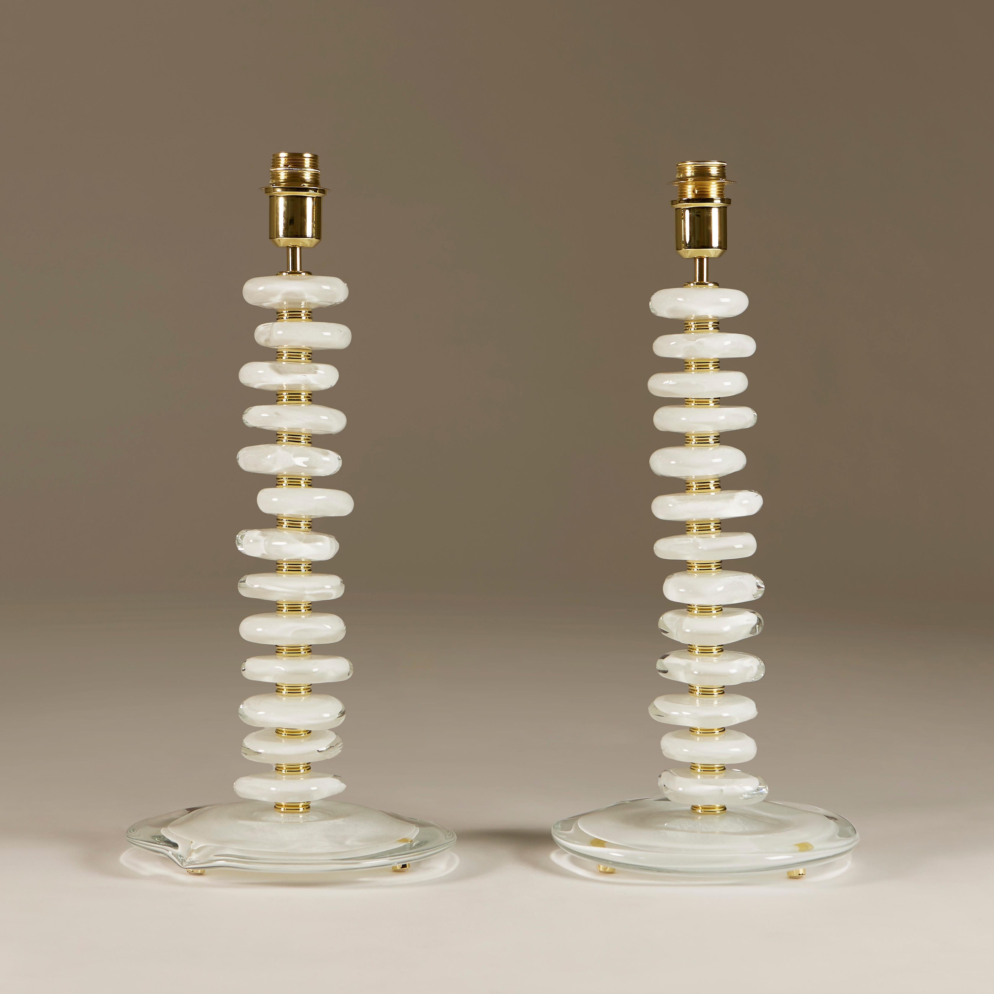 Substantial pair of contemporary table lamps. Each lamp consists of 12 handmade smooth sculptured pebbles. Each pebble is interspersed with double ribbed sections of brass and a brass lamp fitting. Sits on an organic shaped glass base with gold