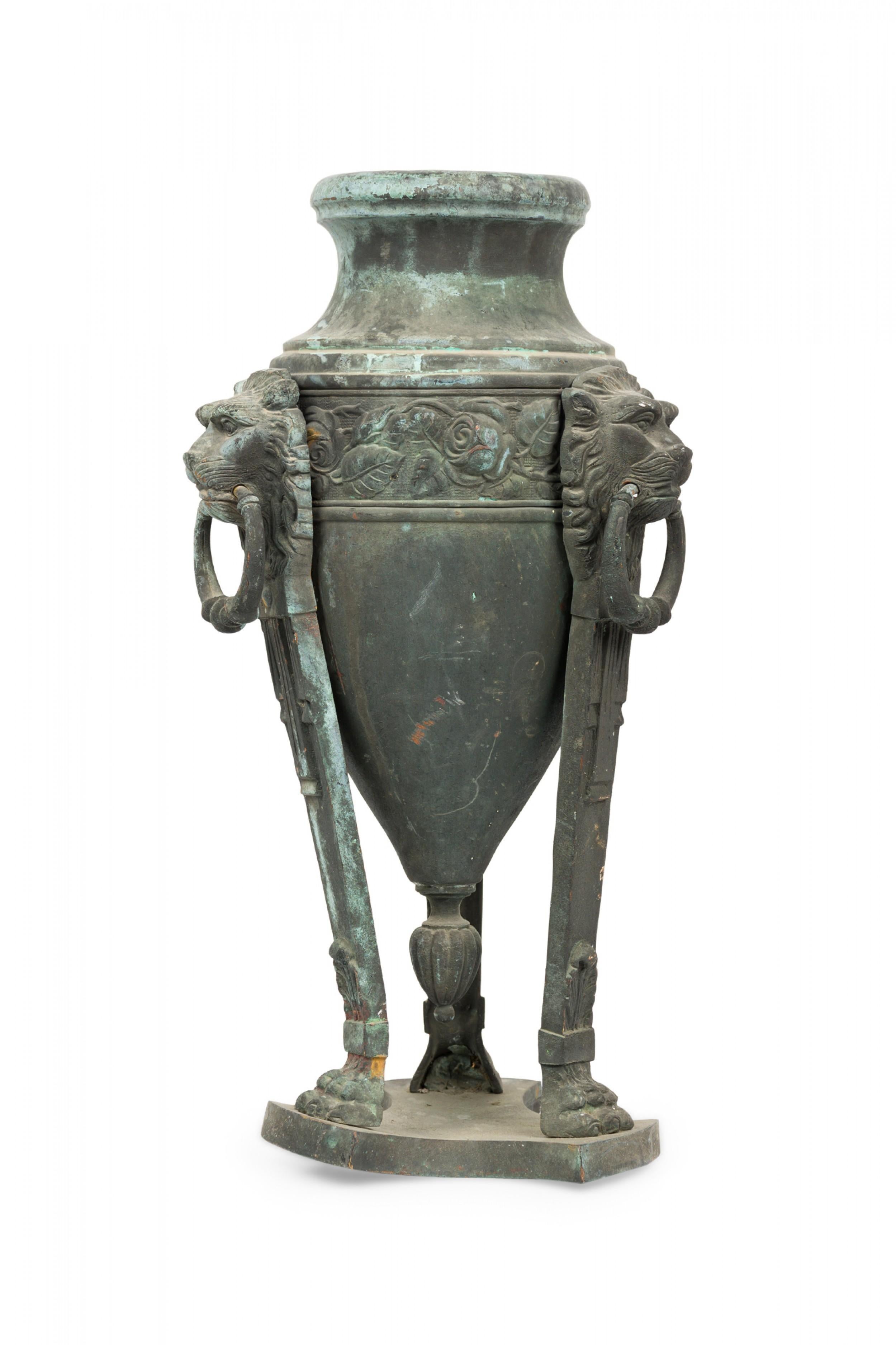 PAIR of Italian neoclassic (19th century) bronze Athenian form urns with natural patina, featuring lions\' head embellishments with ring handles, resting on three lions feet joined by a triangular base (PRICED AS PAIR).