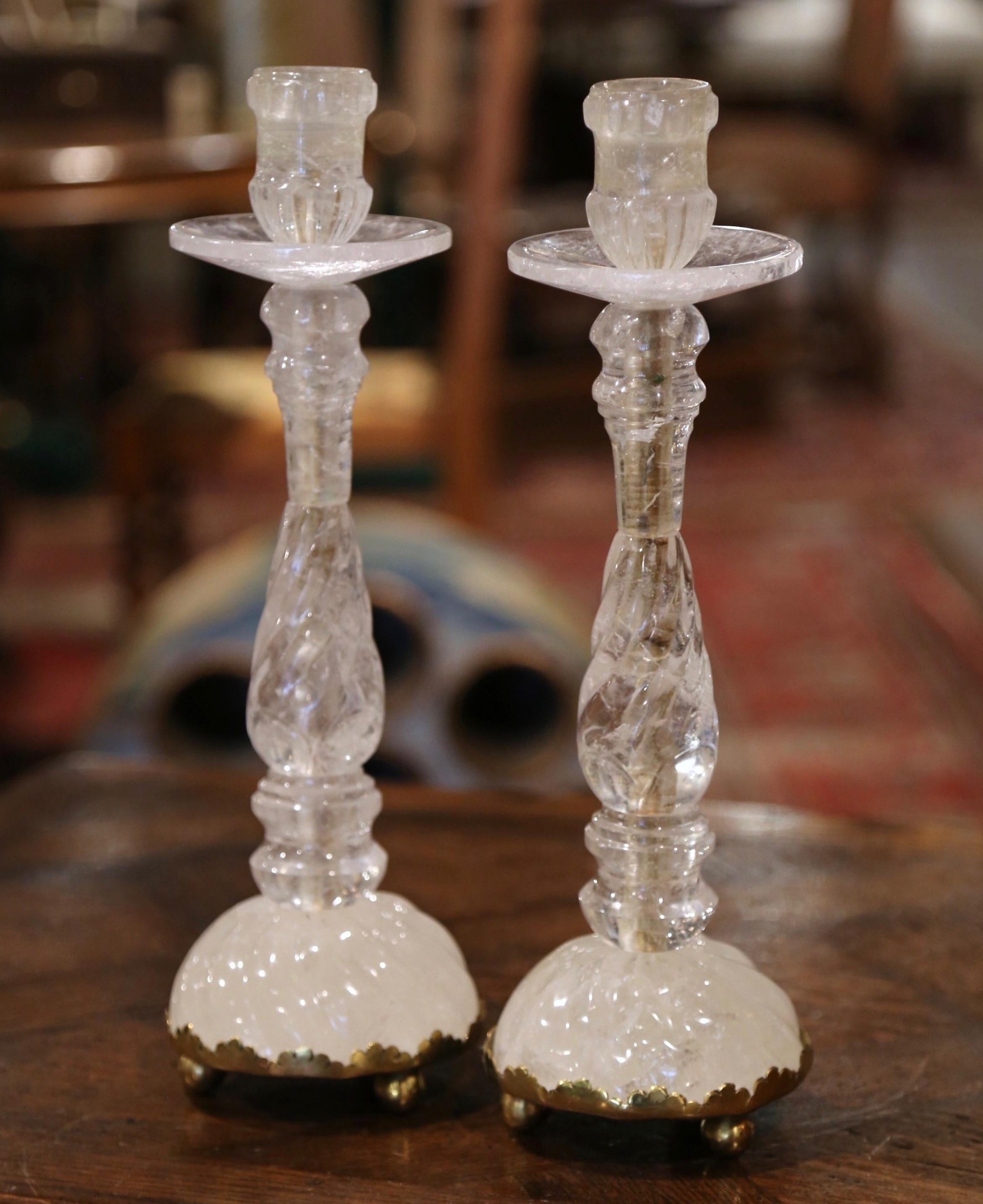 These elegant rock crystal candlesticks were crafted in Italy. Each vintage candle holder sits on a sturdy round brass base dressed with ball feet, and features exquisite craftsmanship throughout. The candlesticks have a carved tapered and twisted