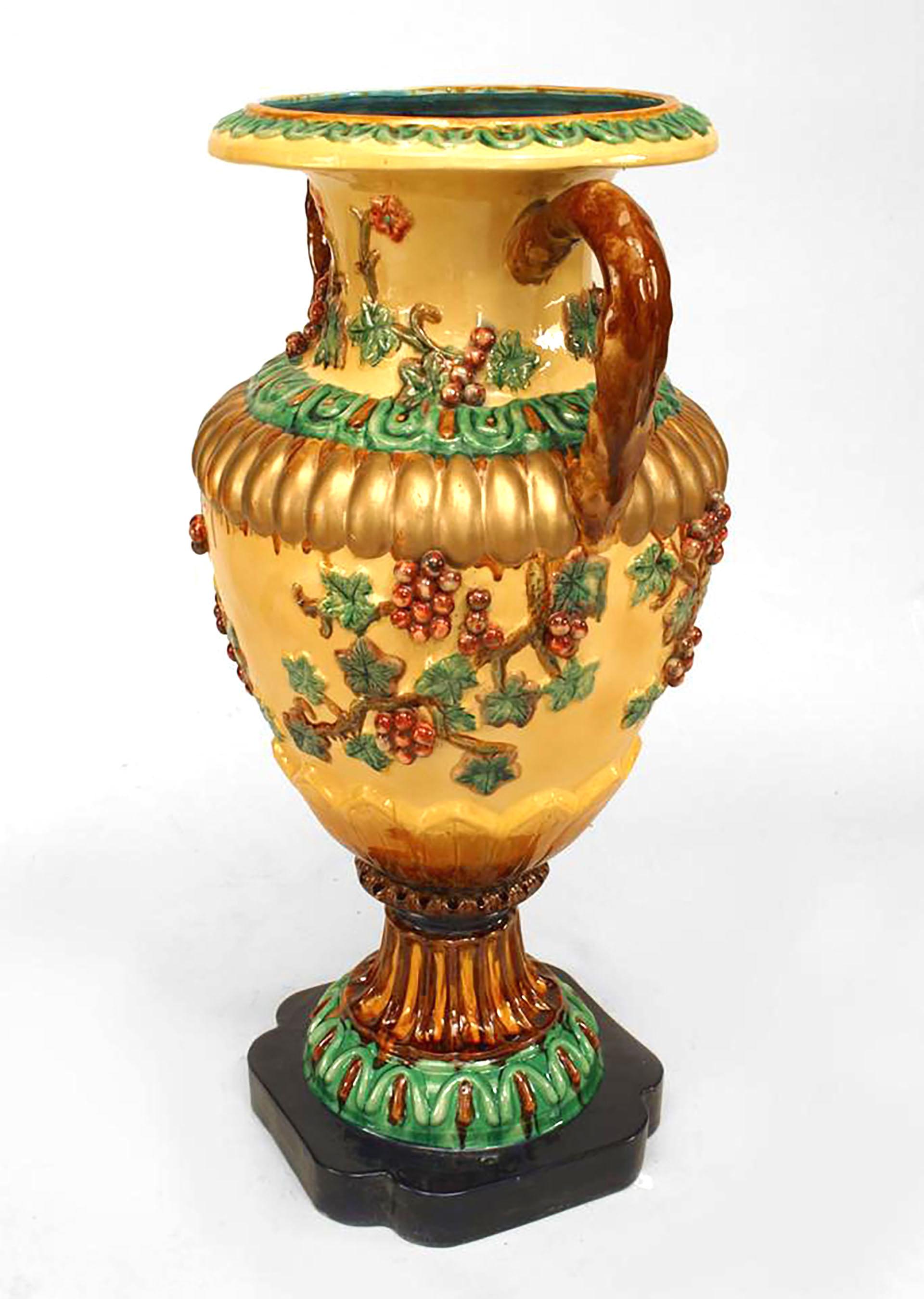 Coppia di vasi da terra in porcellana smaltata gialla e verde in stile neoclassico (19/20° secolo). Con grandi manici marroni e decorazione floreale con uva in rilievo su una base quadrata blu. (Prezzo per la coppia).
  