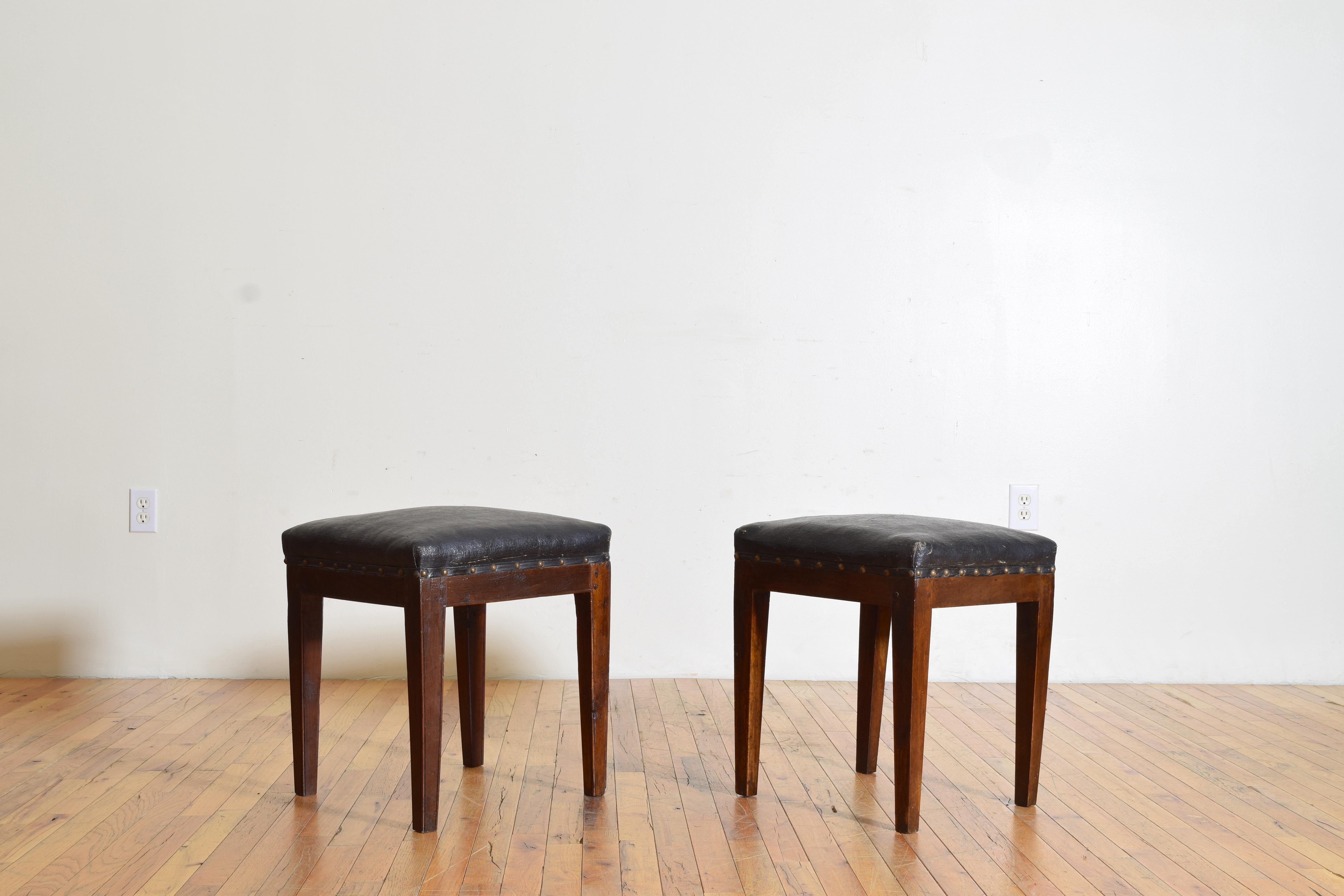 Das Paar hat quadratische, mit antikem Wachstuch bezogene Tischplatten mit Nagelkopfverzierung und steht auf quadratischen, spitz zulaufenden Beinen. 