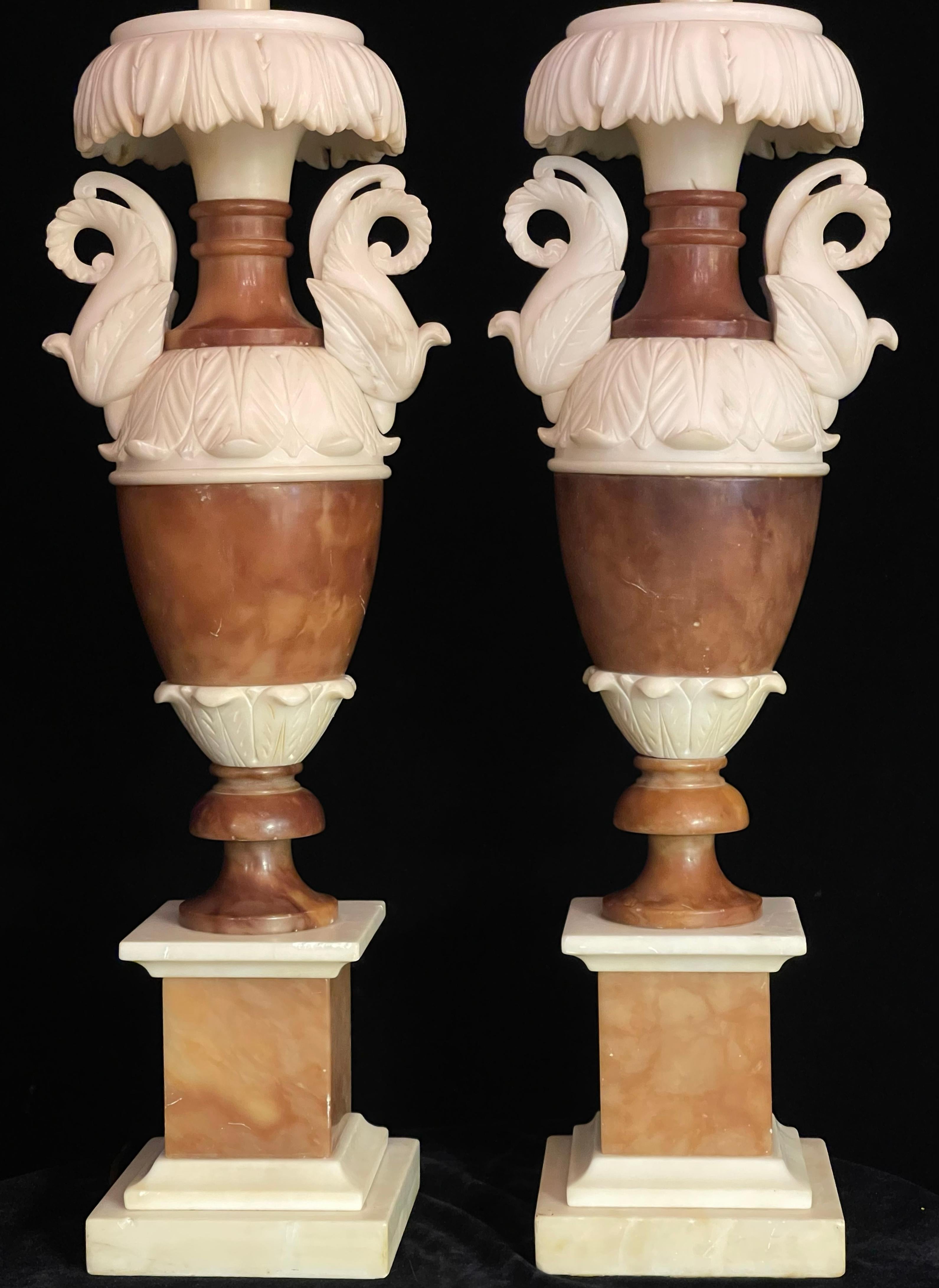 A beautifully sculpted pair of Italian neoclassical hand carved alabaster lamps, distinguished by their harmonious use of two contrasting tones: a richly veined brown and a soft, creamy white. Each lamp is modeled in the form of a classical urn,