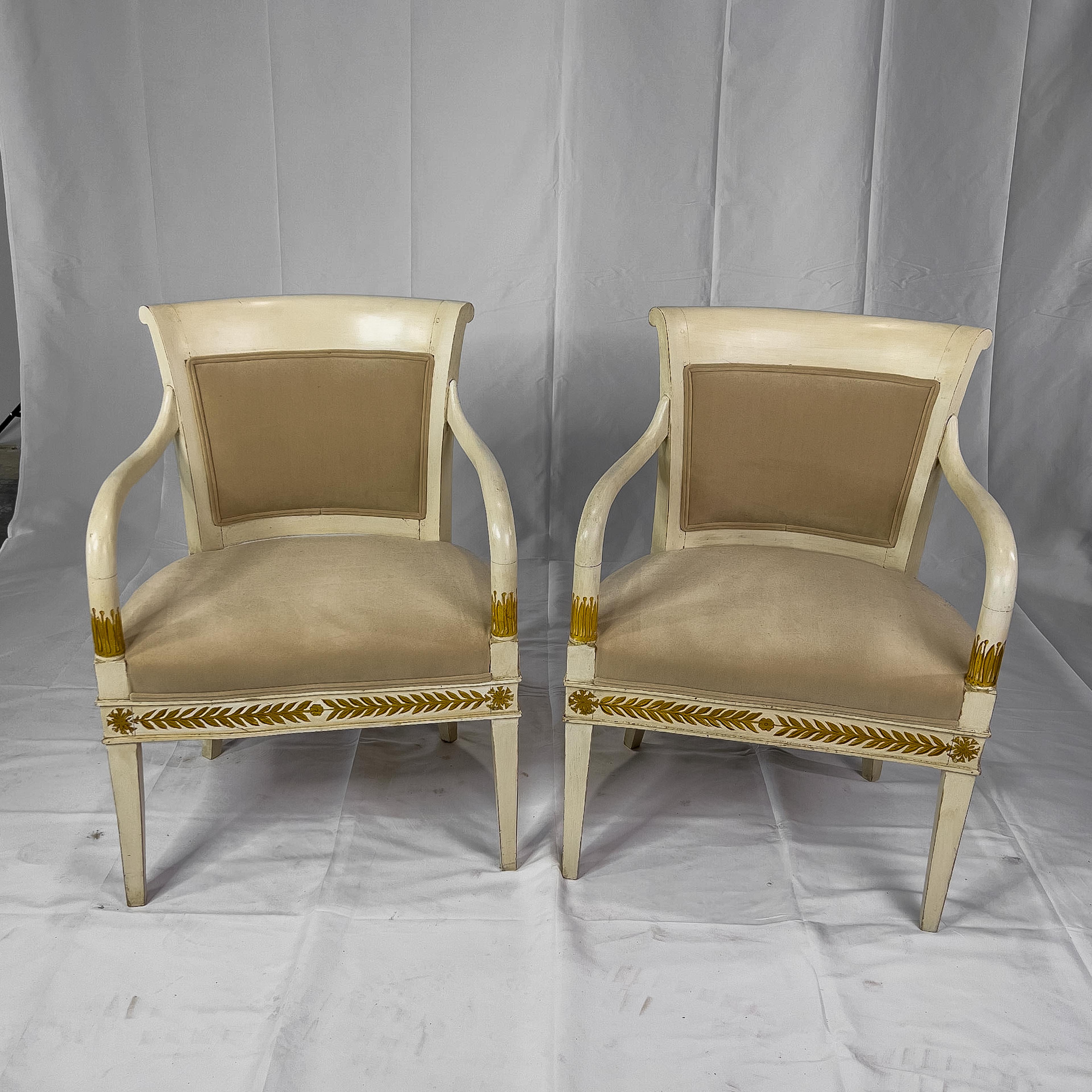 19th century painted Italian armchairs in Neoclassical style having gilt detail, a rounded back, upholstered seat and curvaceous arms.