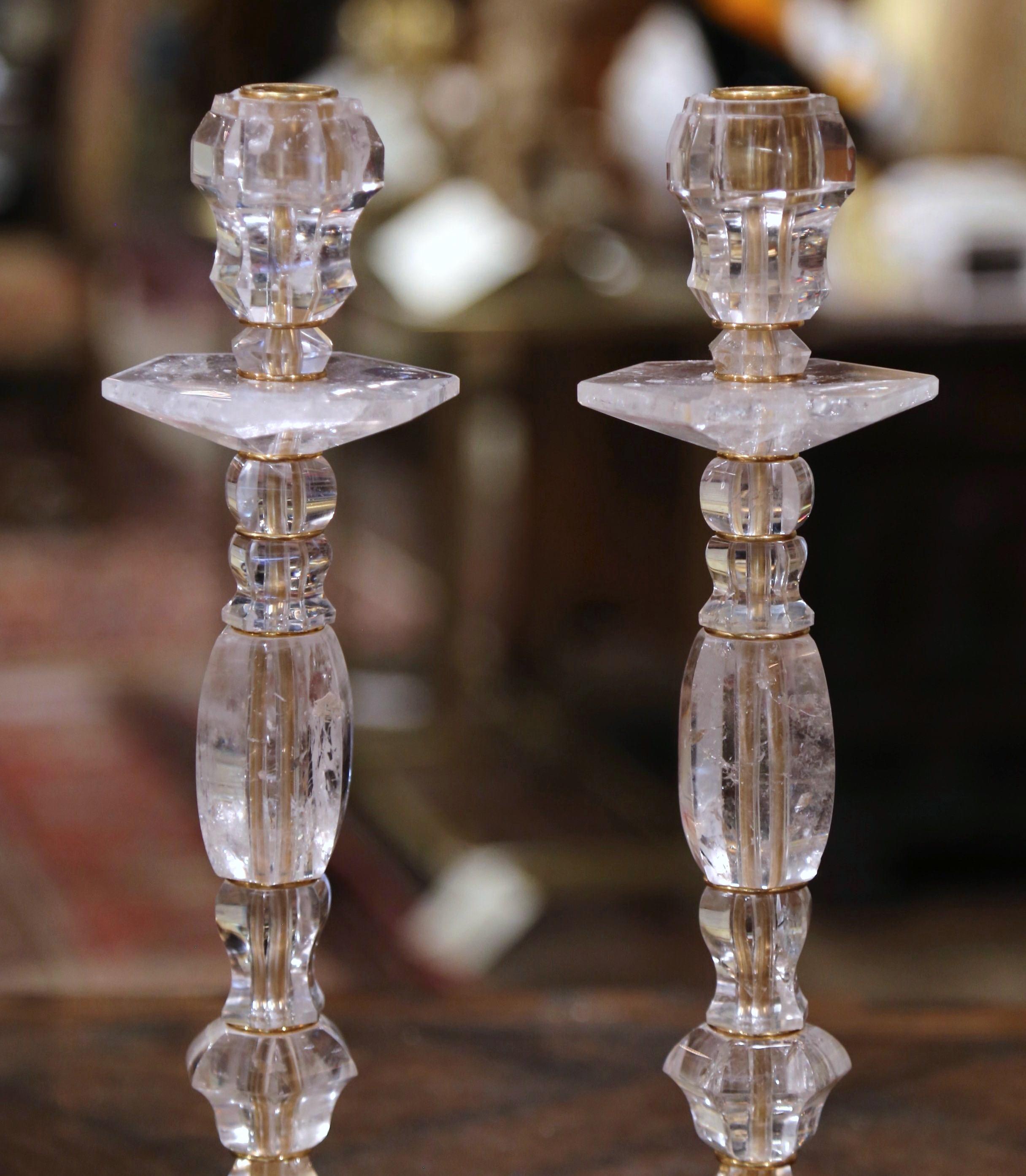 These elegant rock crystal candlesticks were crafted in Italy. Each vintage candleholder sits on a sturdy octagonal brass base dressed with eight ball feet, and features exquisite craftsmanship throughout. The candlesticks have a carved tapered and