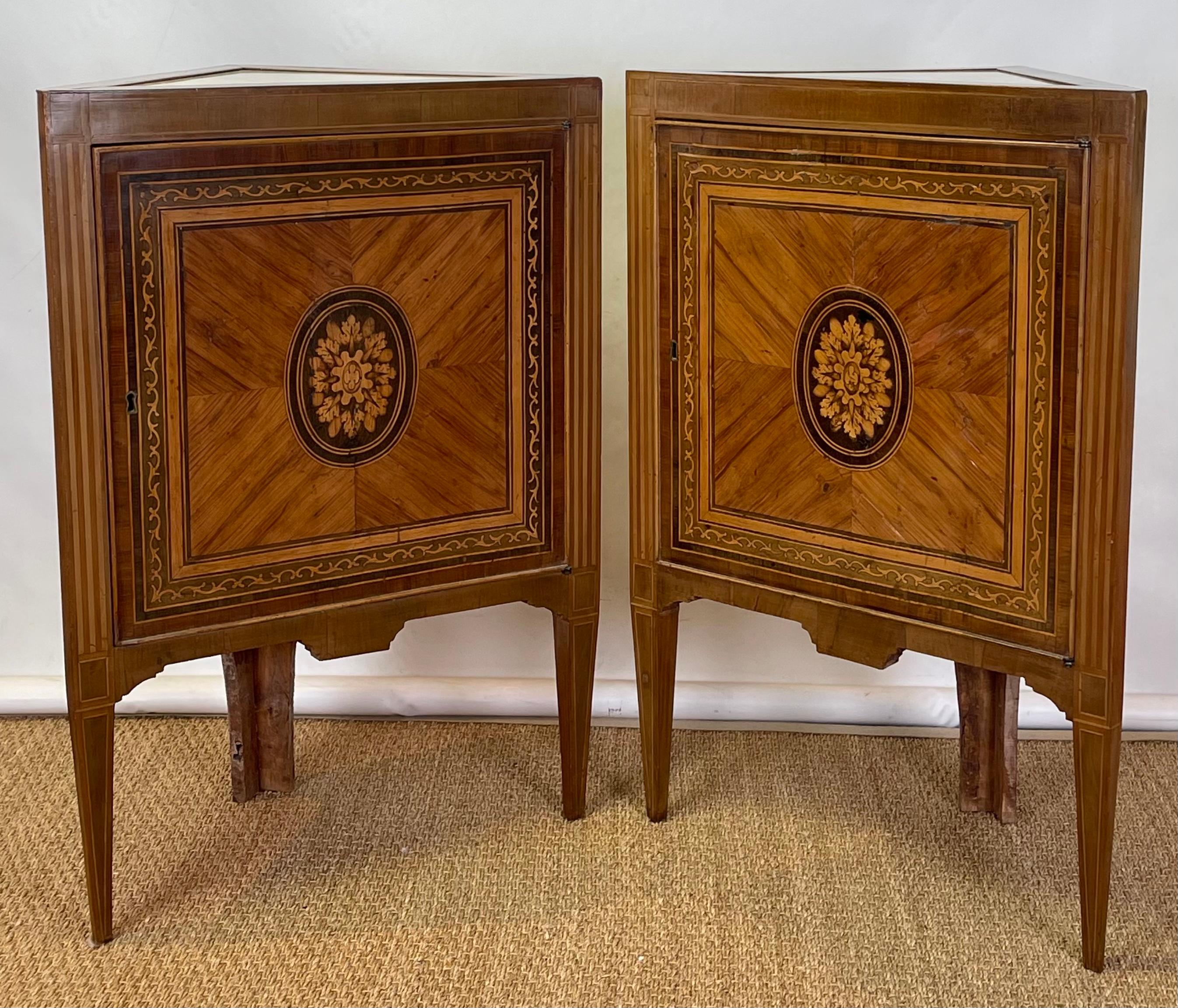 A fine pair of early 19th C. Italian Neoclassical corner cabinets with inset marble tops and marquetry inlaid doors resting on square tapering legs.