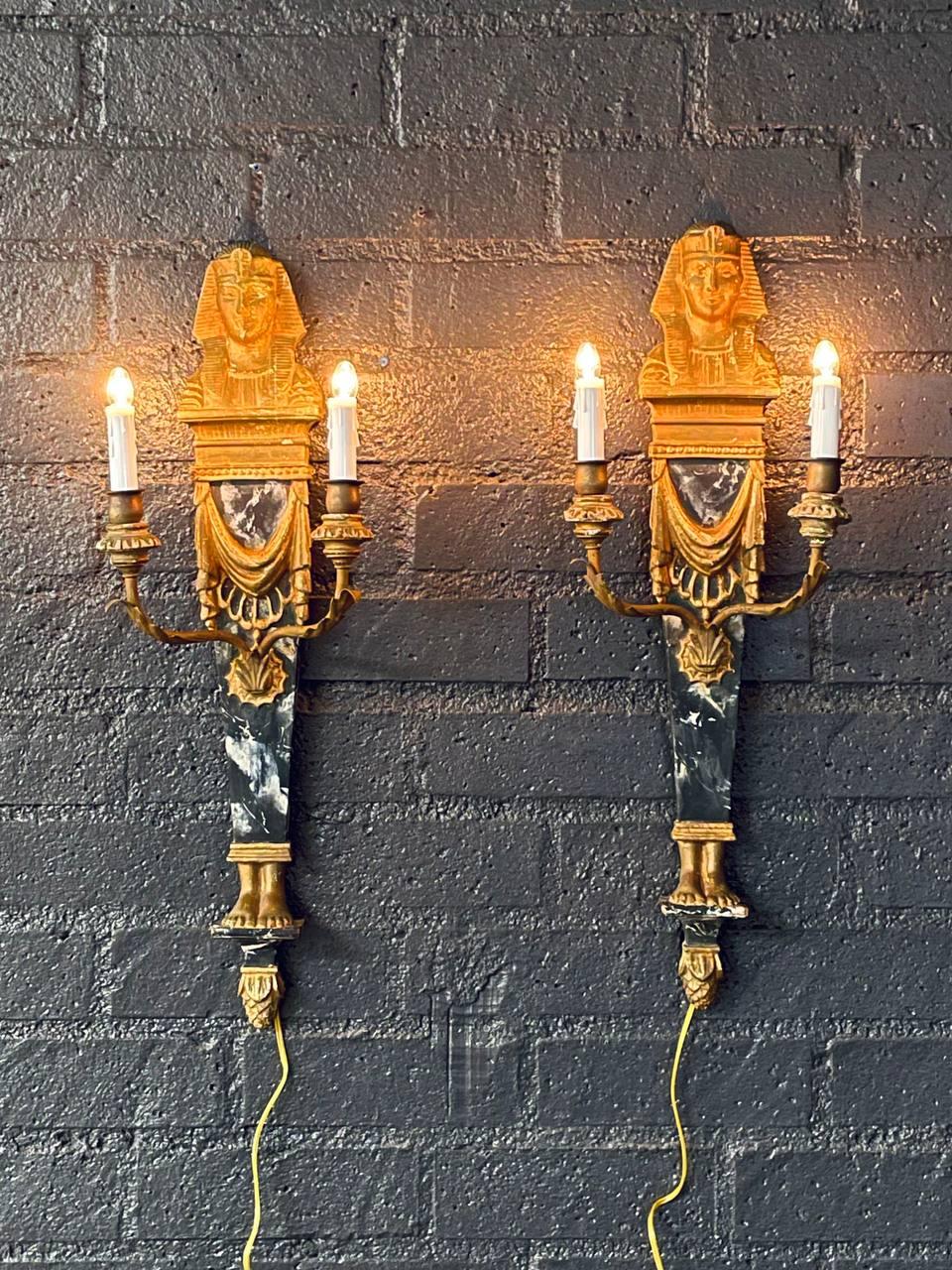 Estado: Estado original de época

Materiales: Madera tallada dorada, paneles de madera imitación mármol negro, brazos de metal dorado
Estilo: Neoclásico renacimiento egipcio

Pareja de apliques neoclásicos italianos de madera dorada de renacimiento