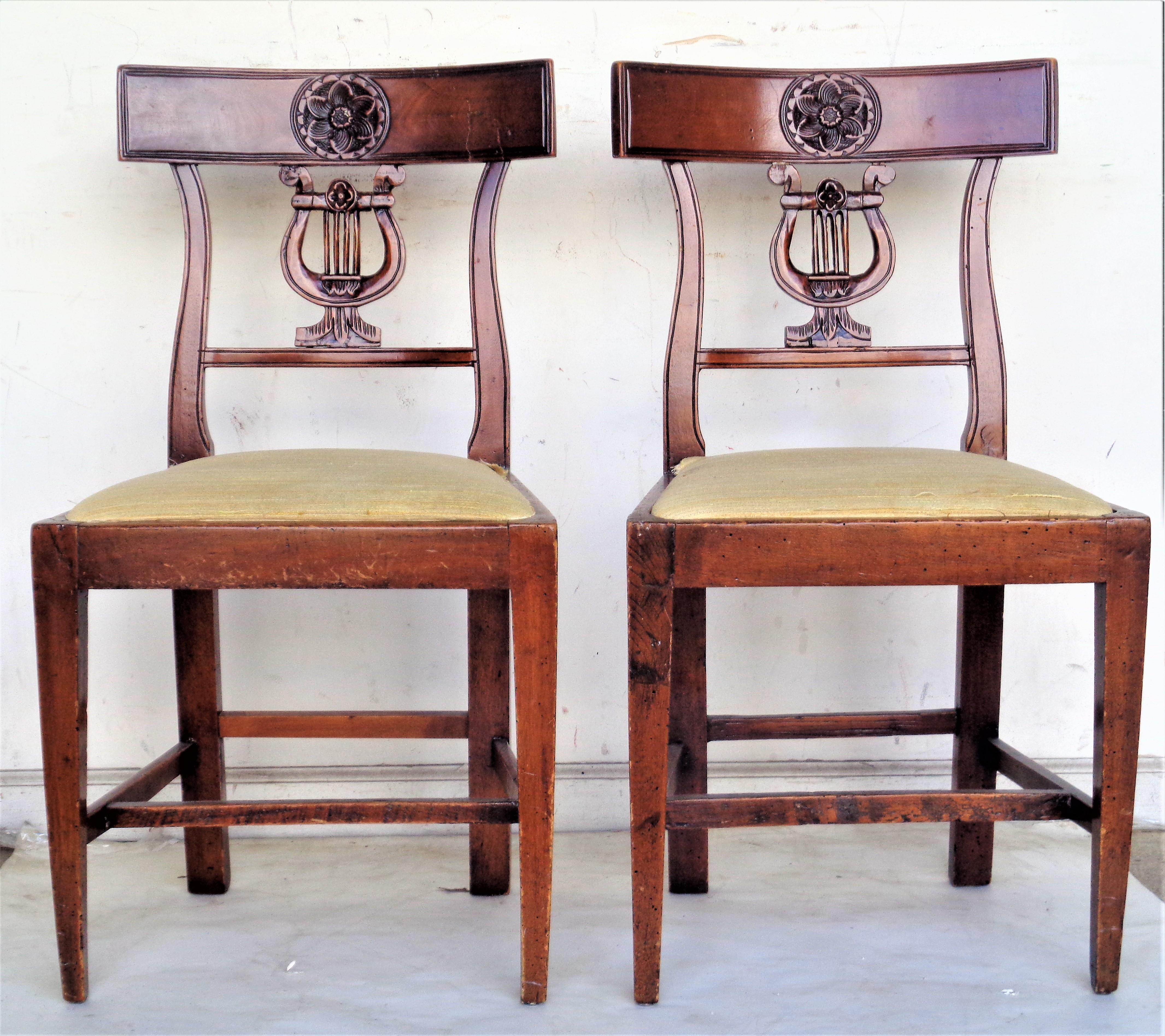 Paire d'anciennes chaises italiennes néoclassiques à dossier lyre sculpté à la main avec rosette sculptée au centre des traverses supérieures incurvées du dossier. Les deux chaises ont été construites au début de l'époque et le bois a pris une