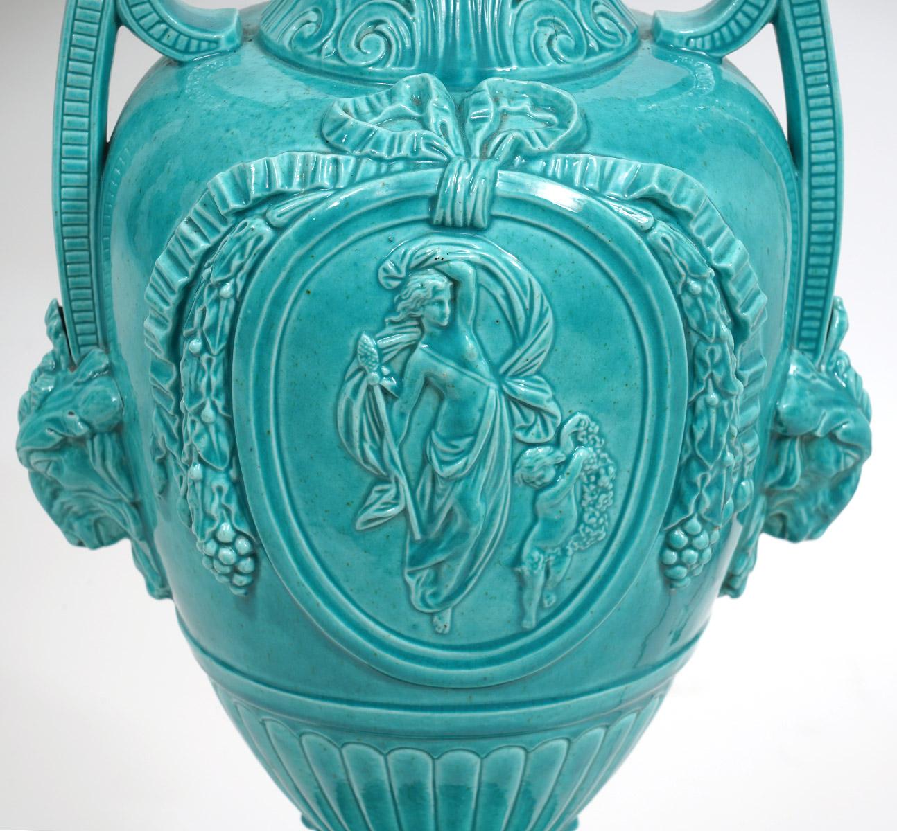 The beautiful Turquoise glaze and the Classical Greek form make these table lamps stand out. They are decorated in high relief with figures, ribbons, rams heads and leaf work standing on circular marble bases. Likely late 19th century.